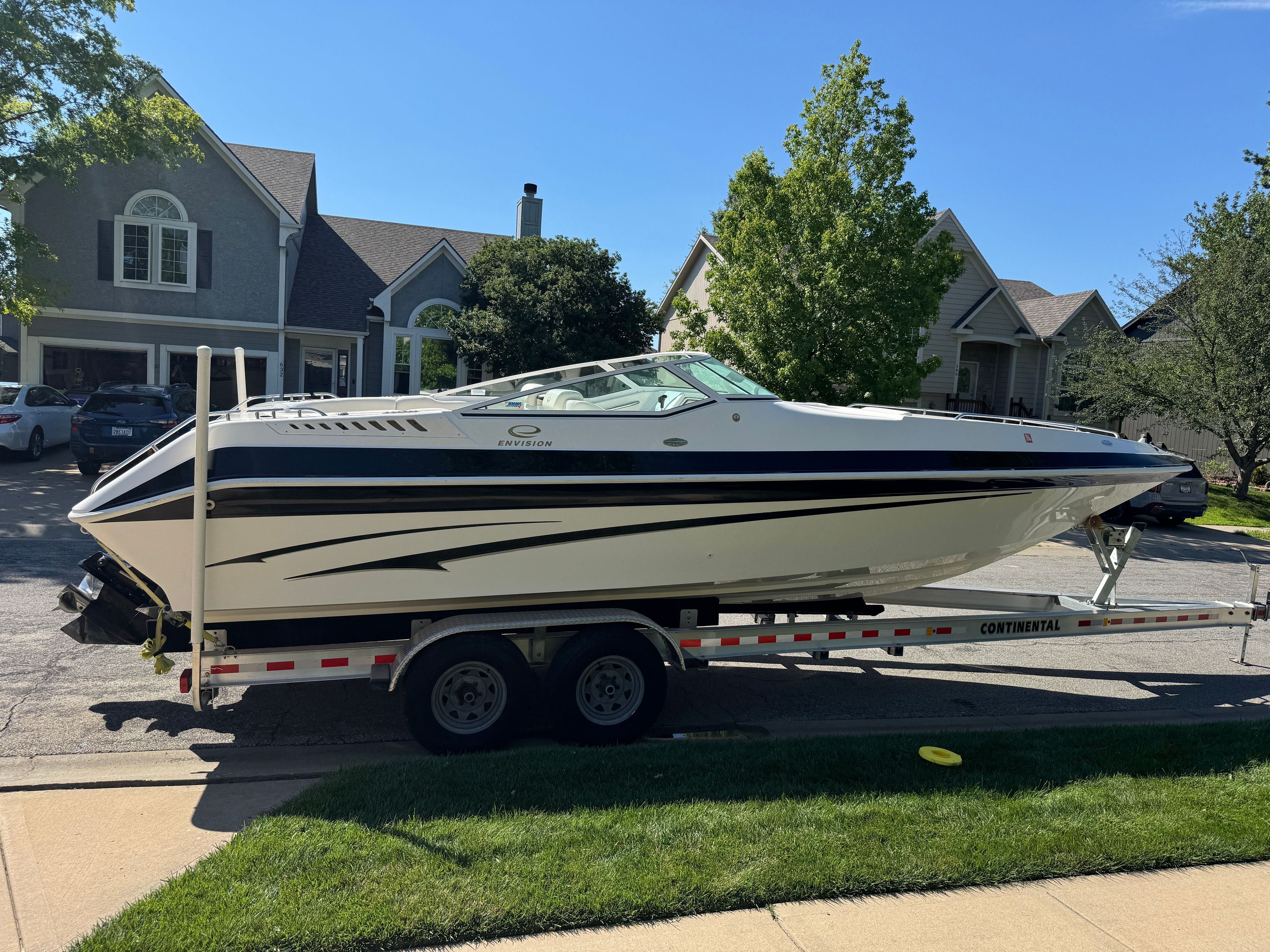 A 2003 Envision 2900 DLX boat on a trailer in a residential area.