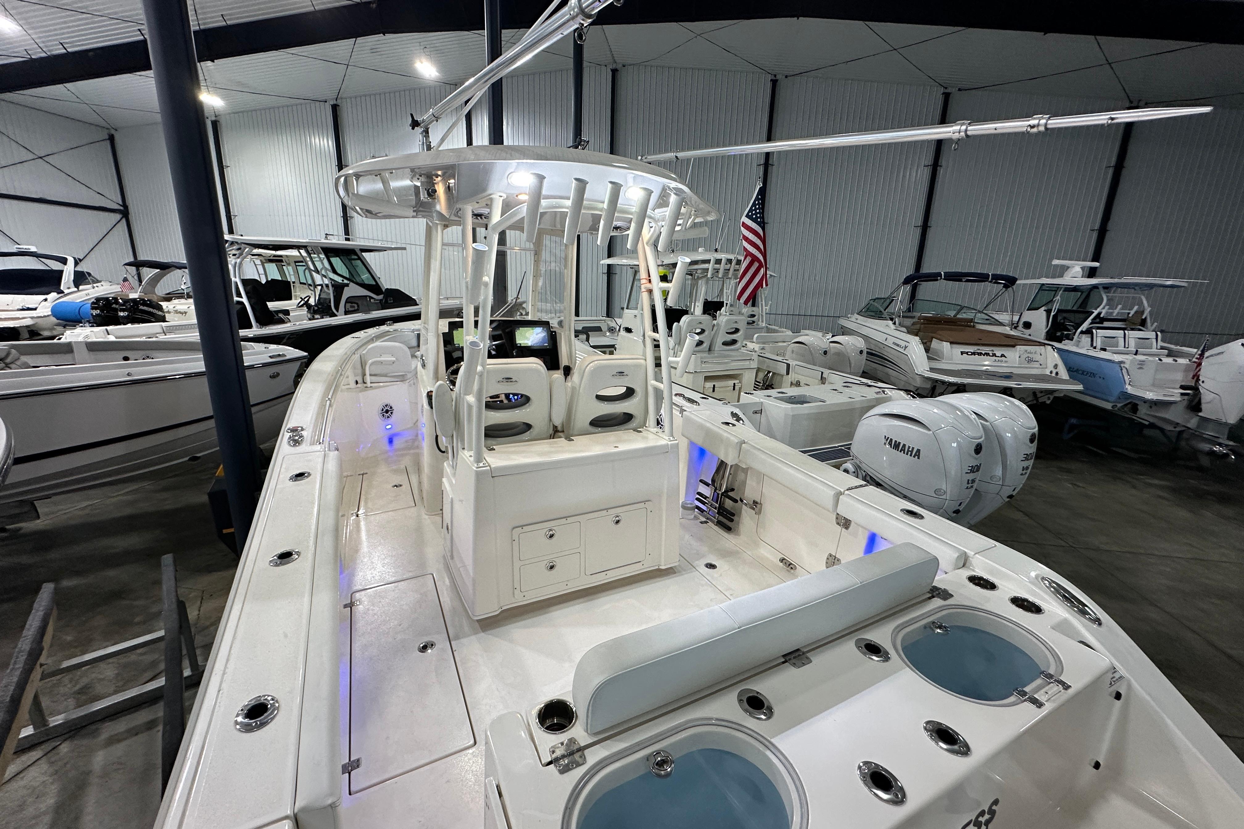 2024 Cobia 301 Center Console boat in showroom, featuring dual Yamaha engines and modern design.