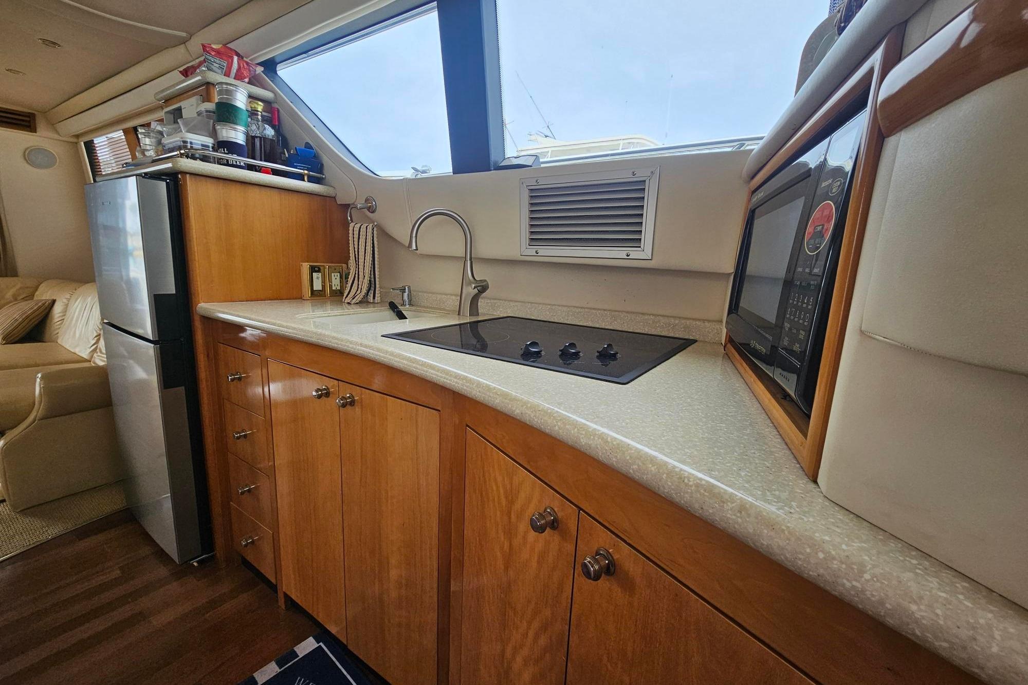 Interior kitchen of 2002 Carver 450 Voyager Pilothouse with stove, microwave, and fridge.