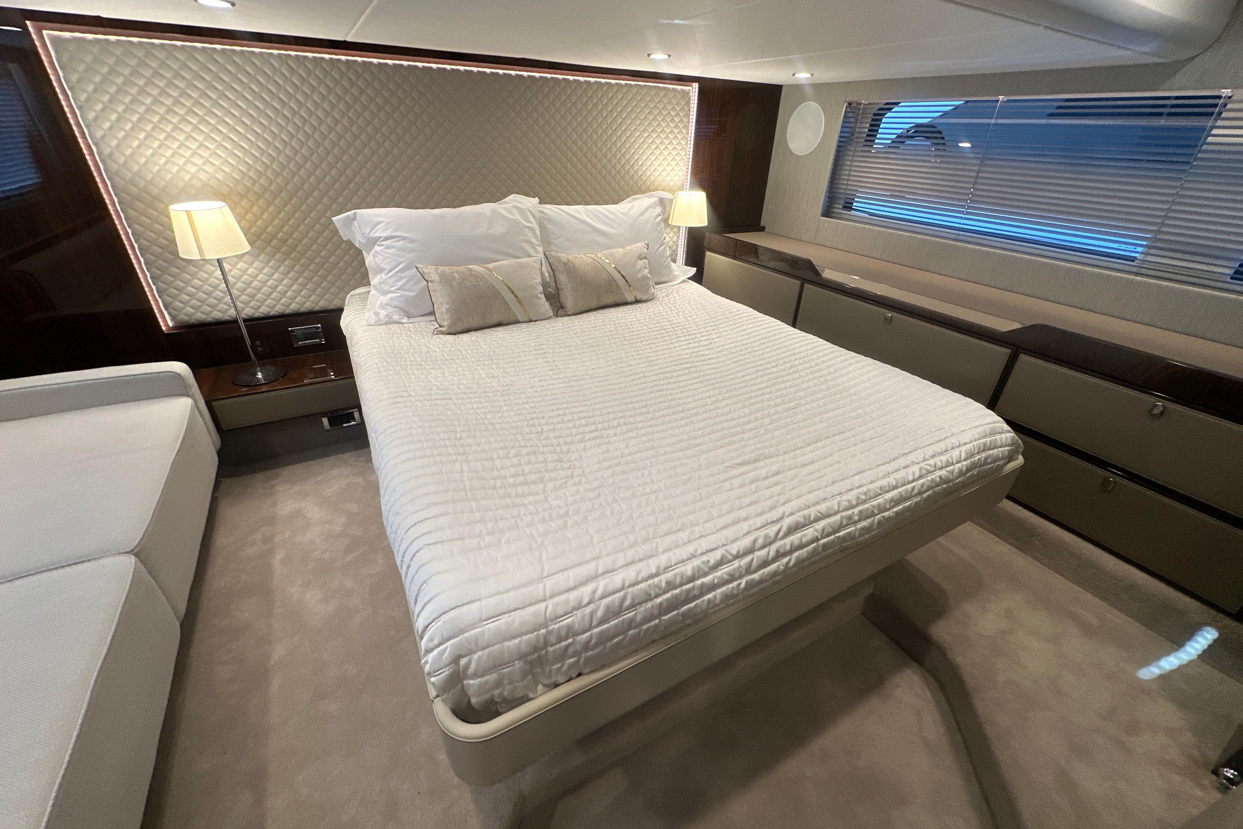 Luxurious bedroom interior of 2024 Fairline Squadron 50 yacht with elegant bedding and ambient lighting.