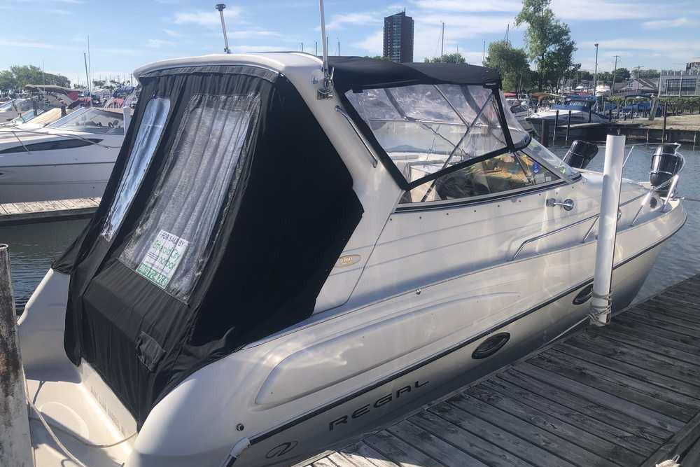 1999 Regal Commodore 2760 boat docked at marina with black canopy and clear windows.