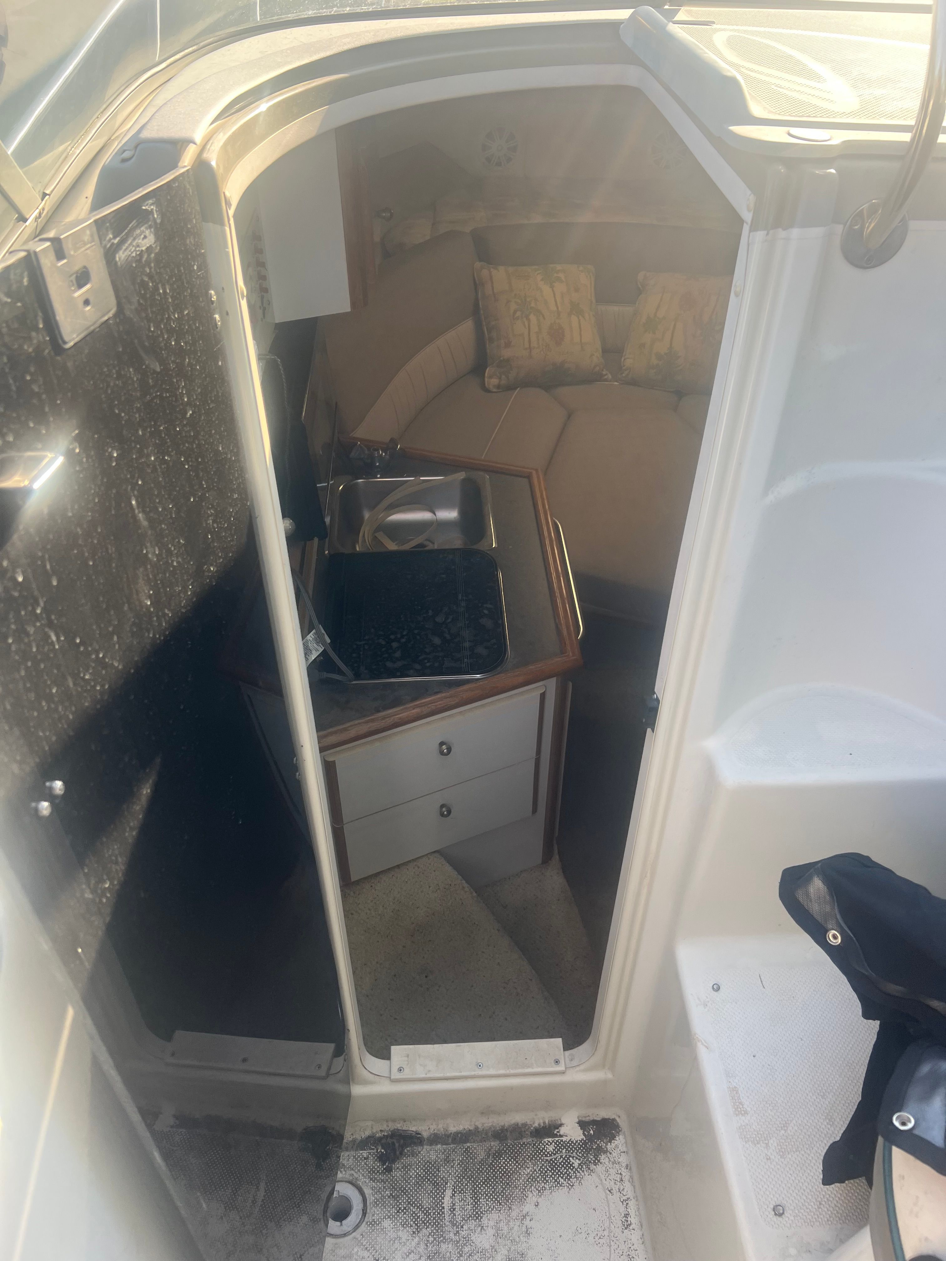 The image shows the interior of a boat with a small kitchenette and seating area.