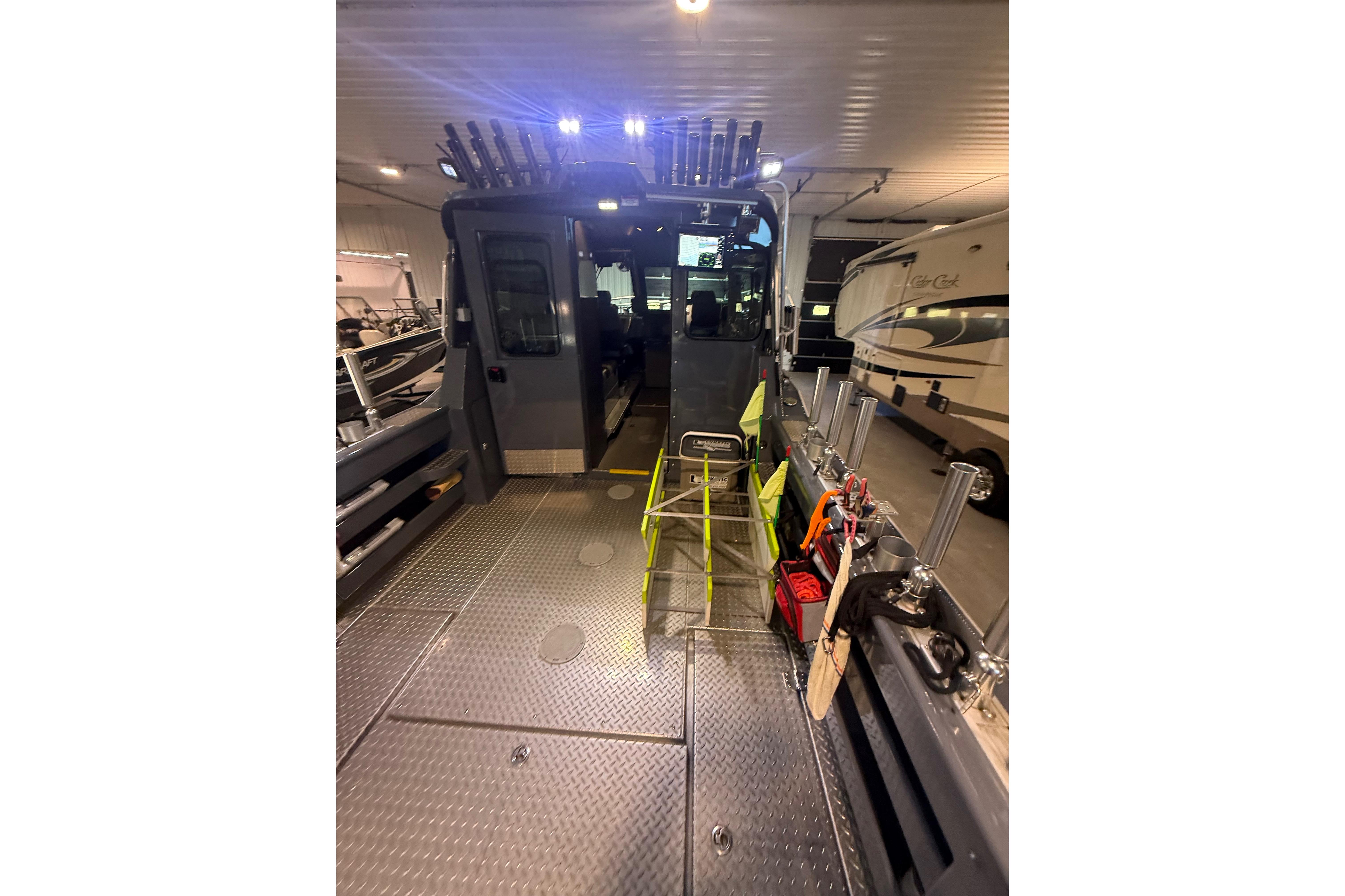 2022 Hewescraft 270 Alaskan Hardtop interior with fishing gear and equipment in a garage.