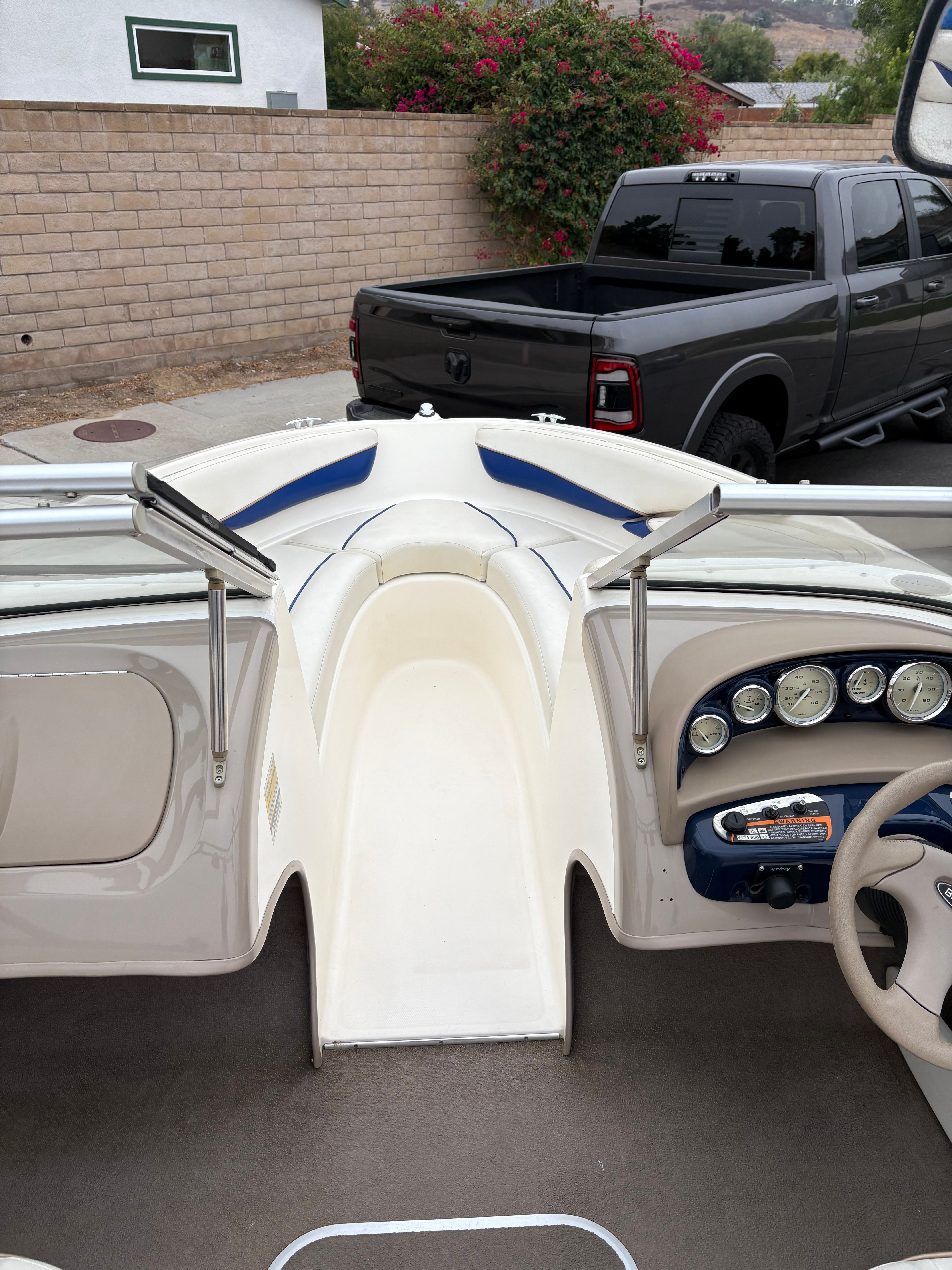 2003 Bayliner CAPRI 205 boat interior with dashboard and seating, parked near a gray truck.