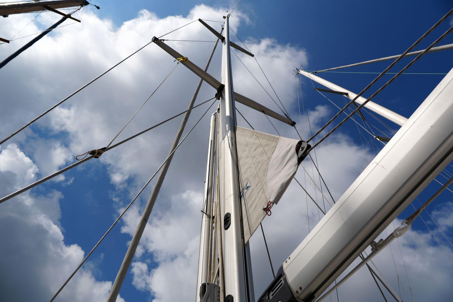 Mast and rigging of a 2005 Hallberg-Rassy 37 sailboat against a cloudy sky.