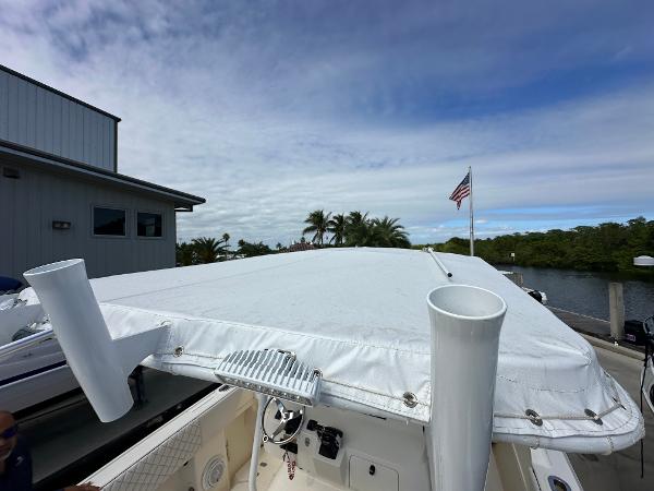2005 Intrepid 323 boat with white cover docked near a building and American flag.