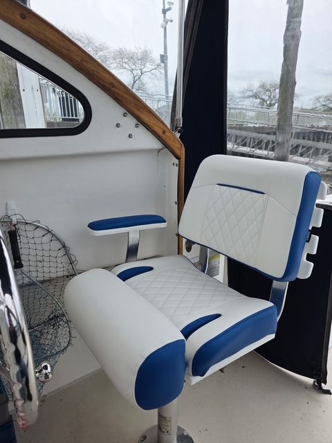 A white and blue boat seat with armrests inside a Steiger Craft boat.