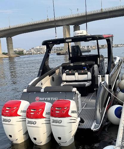 2017 Mystic Powerboats M4200 with triple Mercury 350 engines docked near a bridge.