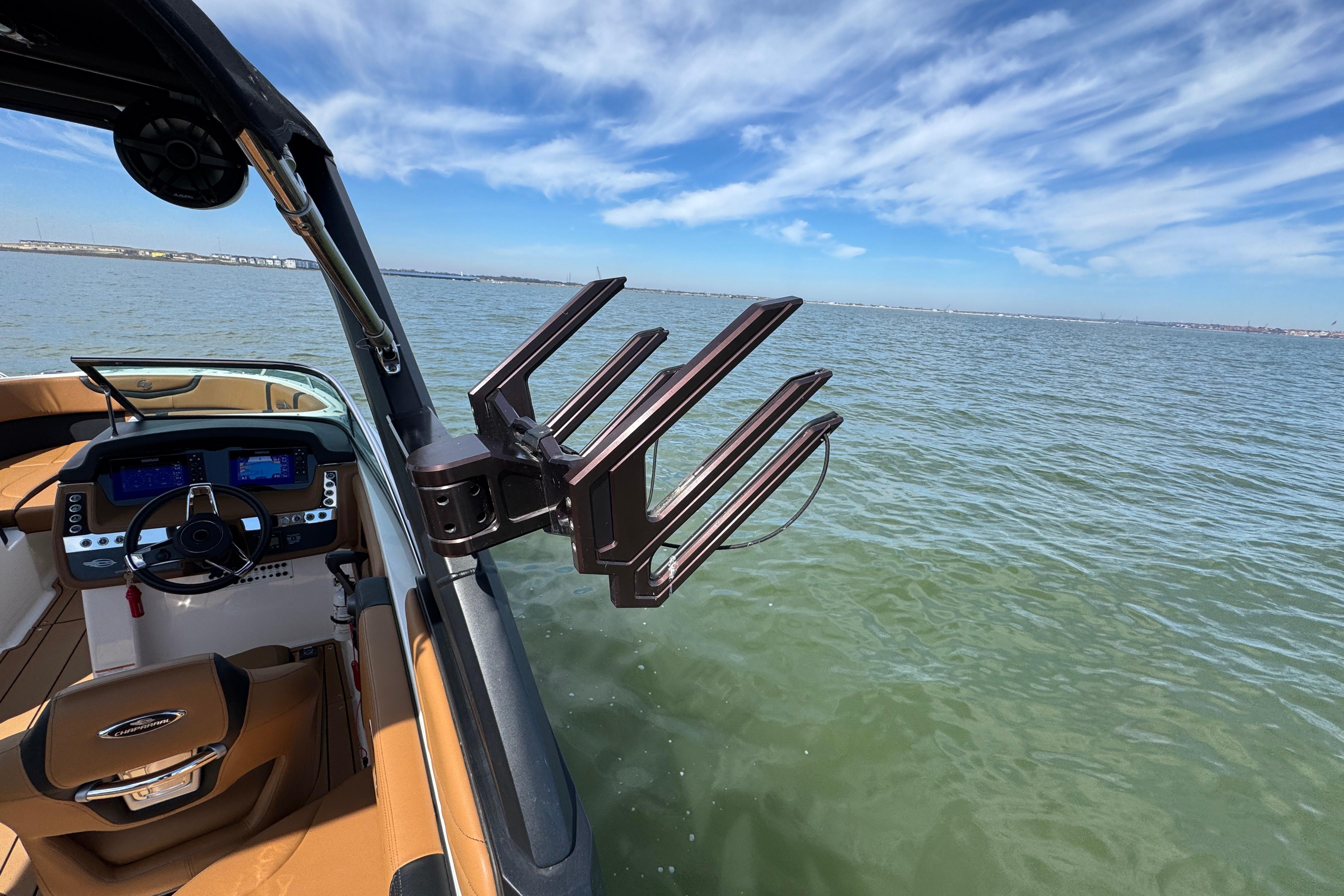 2023 Chaparral 26 Surf boat interior with steering wheel and wakeboard rack on a sunny day.