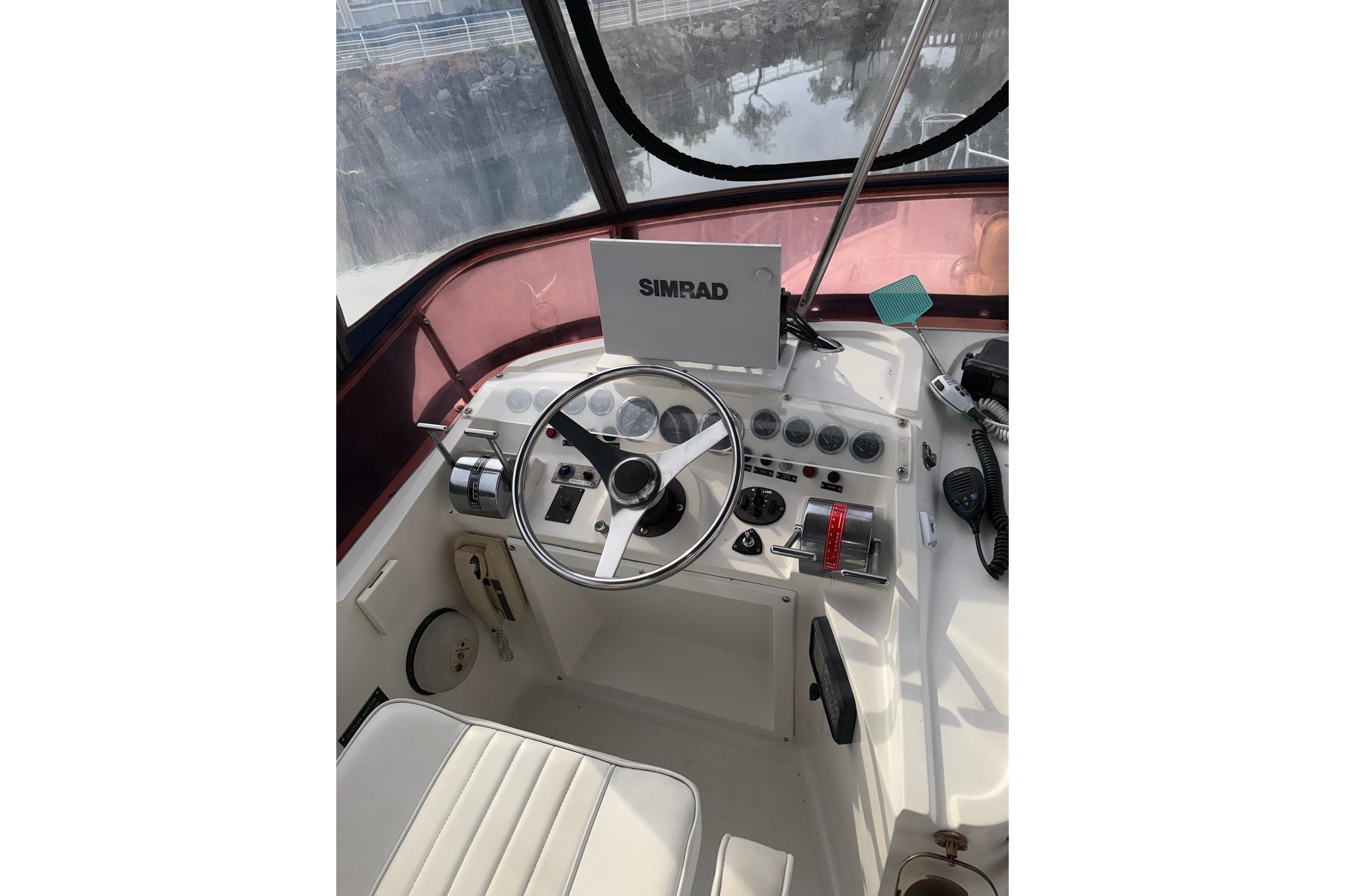 Helm of 1990 Mediterranean Sport Fish boat with steering wheel and navigation equipment.