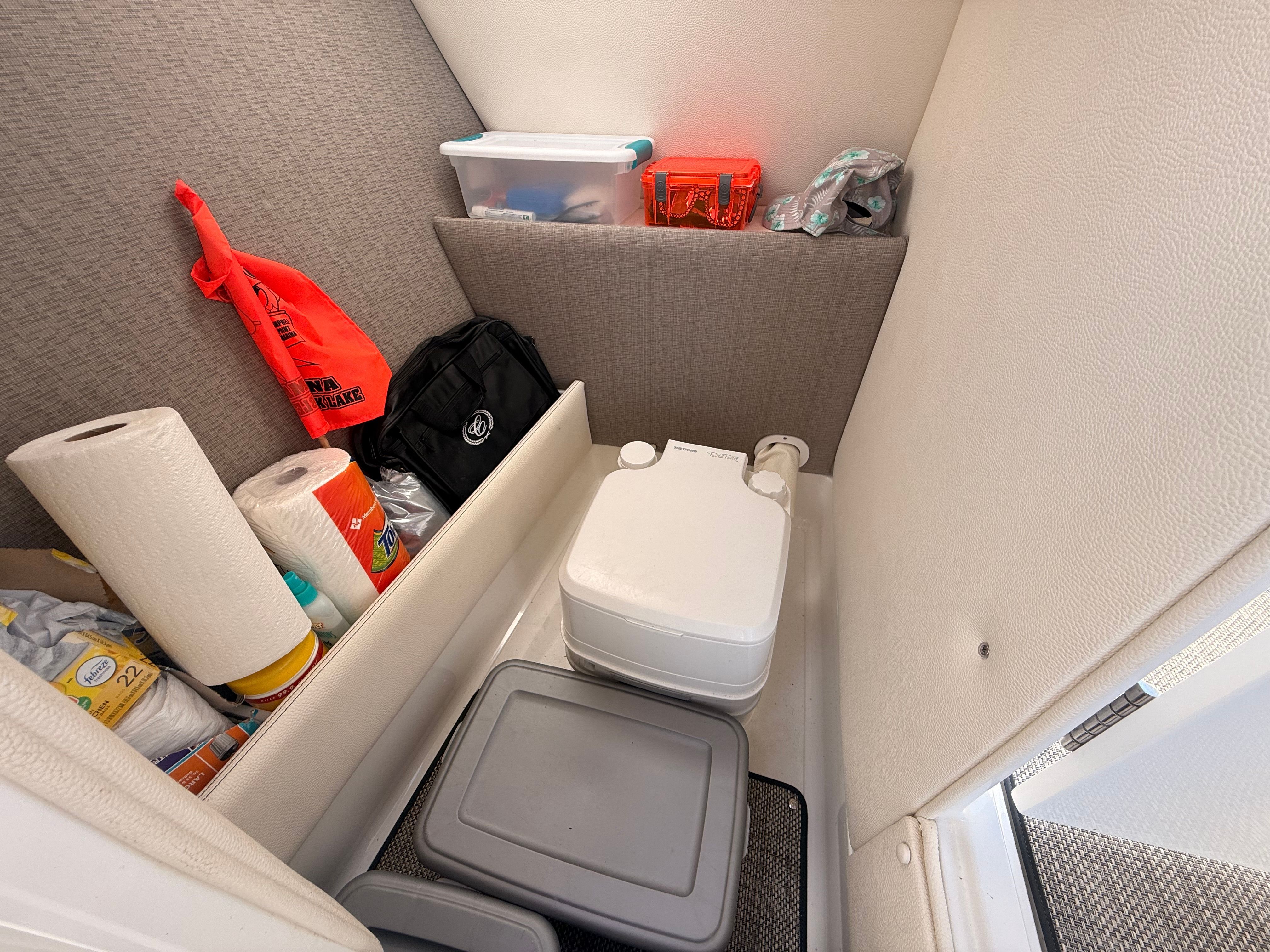 The interior of a 2019 Cobalt R7 Surf features a compact toilet and storage with various items.
