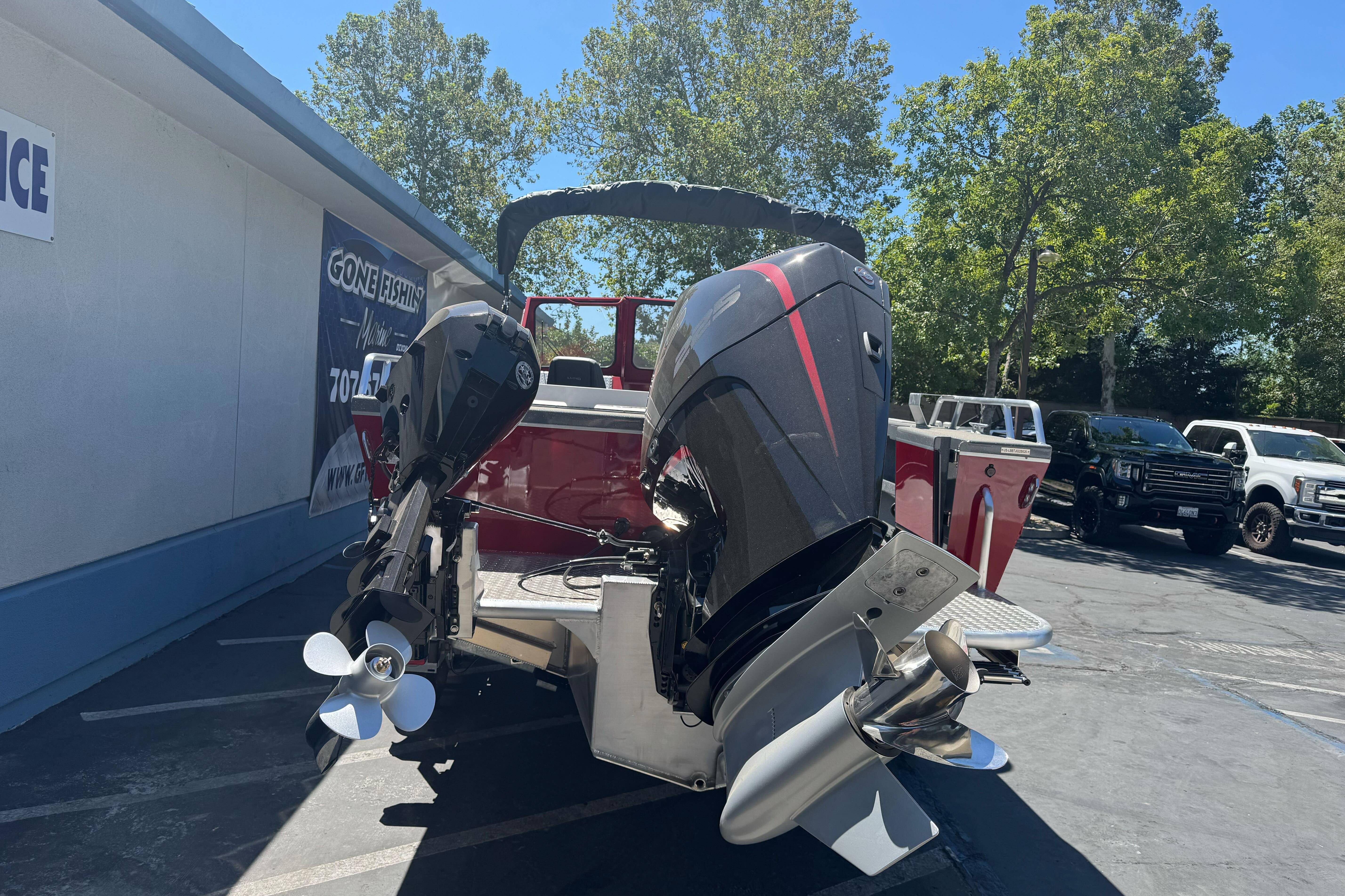 2026 Lund 210 Heavy Gauge boat with dual outboard motors in a parking lot.