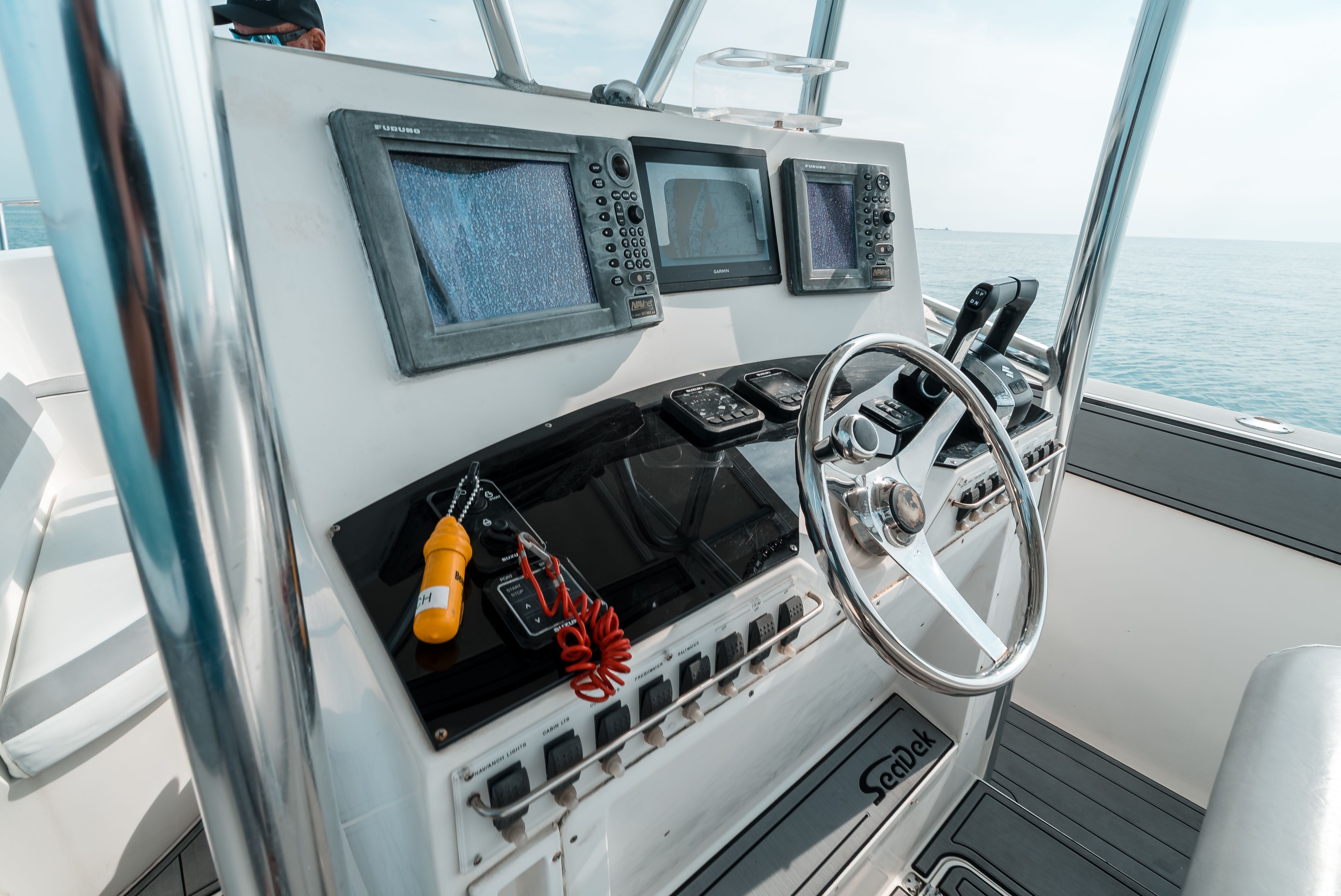 The image shows a boat's helm with multiple screens and a steering wheel.