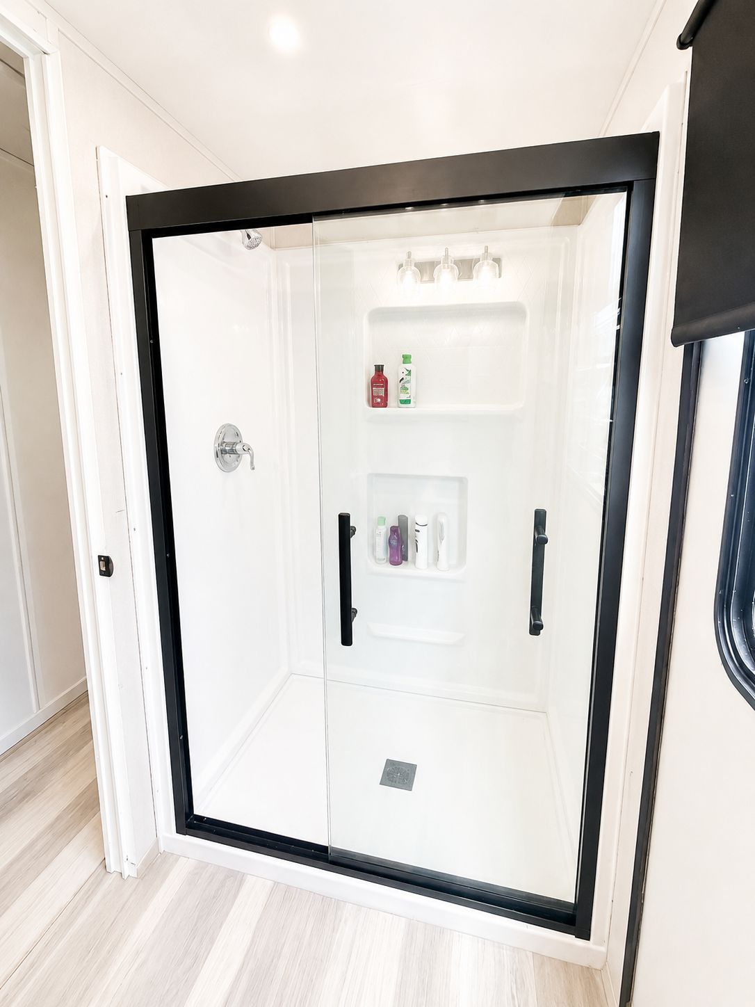 A modern shower enclosure with glass walls and built-in shelves.