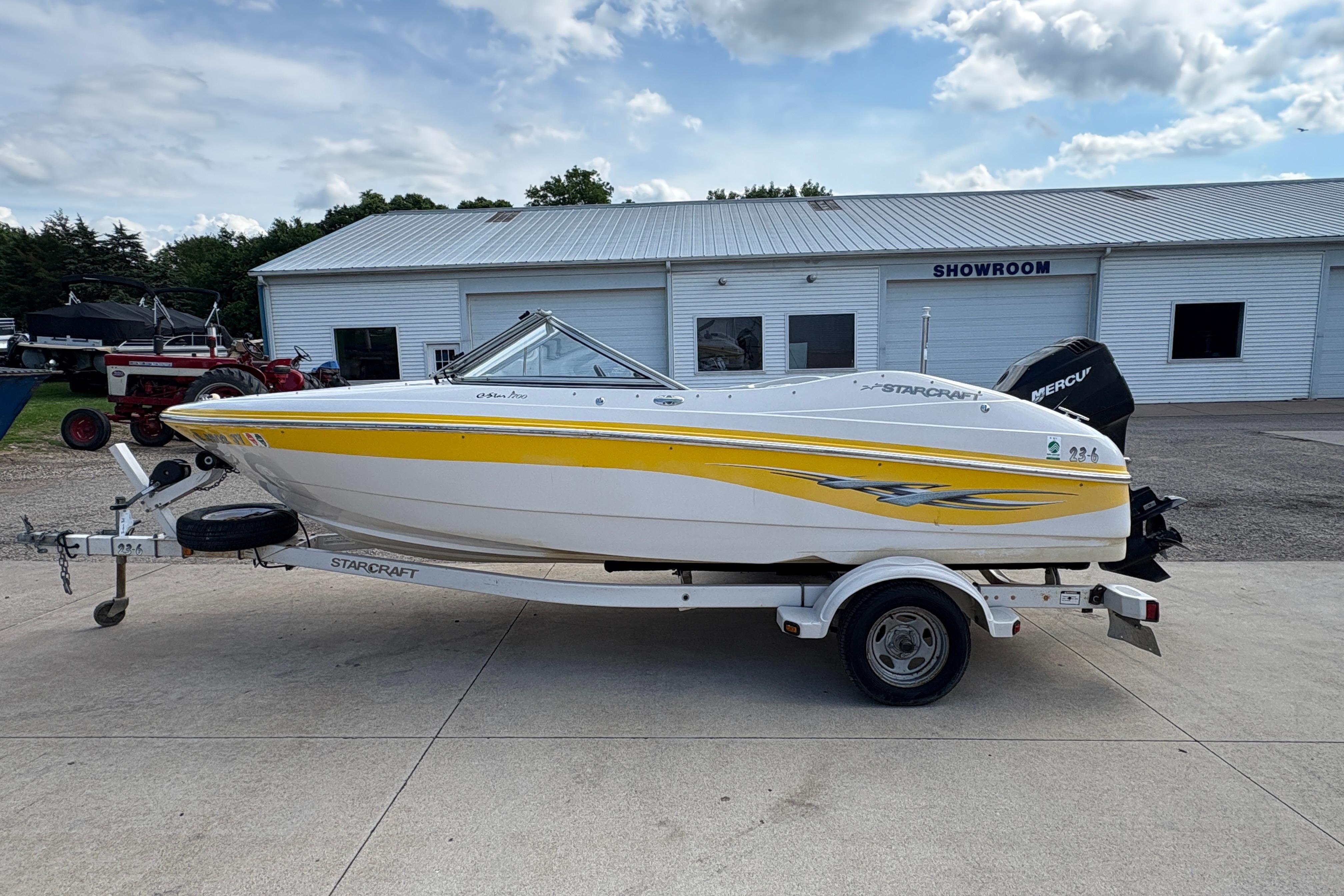 2005 Starcraft C-Star 1700 OB boat with yellow stripe on trailer, parked outside showroom.