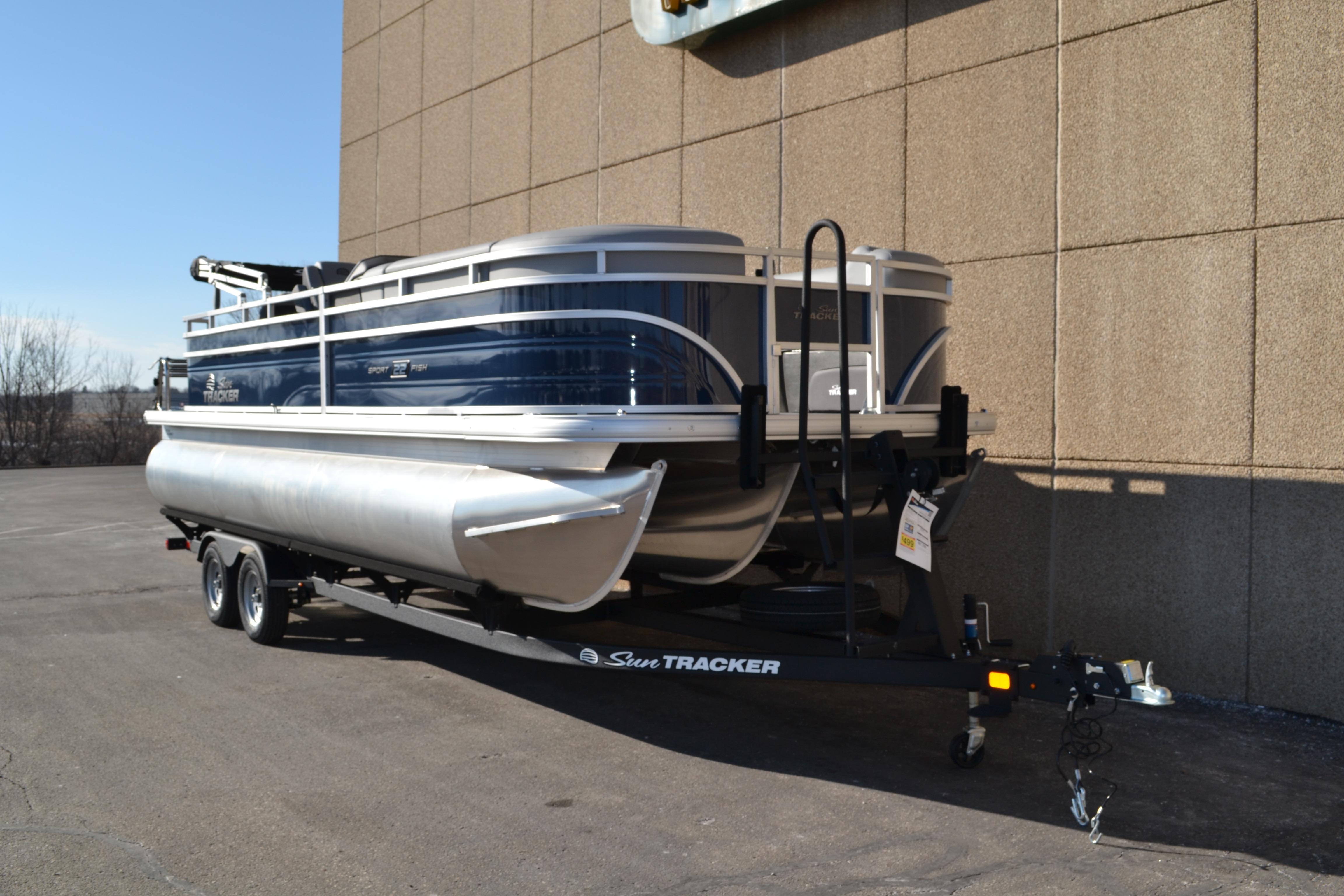 2026 Sun Tracker SportFish 22 XP3 pontoon boat on trailer, parked outdoors.