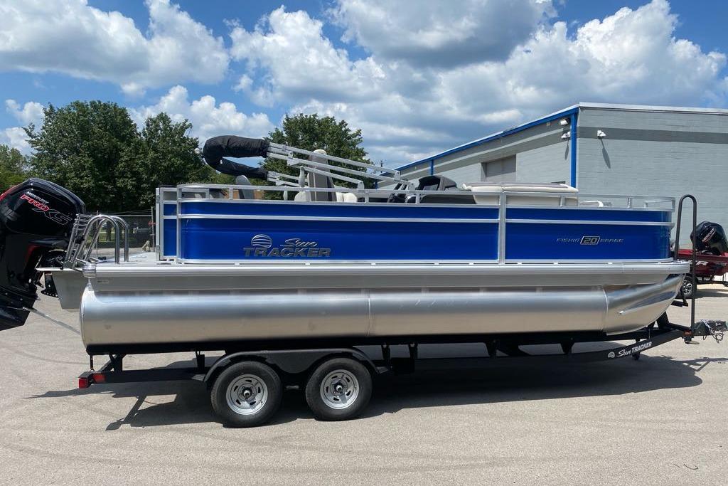 2026 Sun Tracker Fishin' Barge 20 DLX pontoon boat on trailer, parked outdoors.