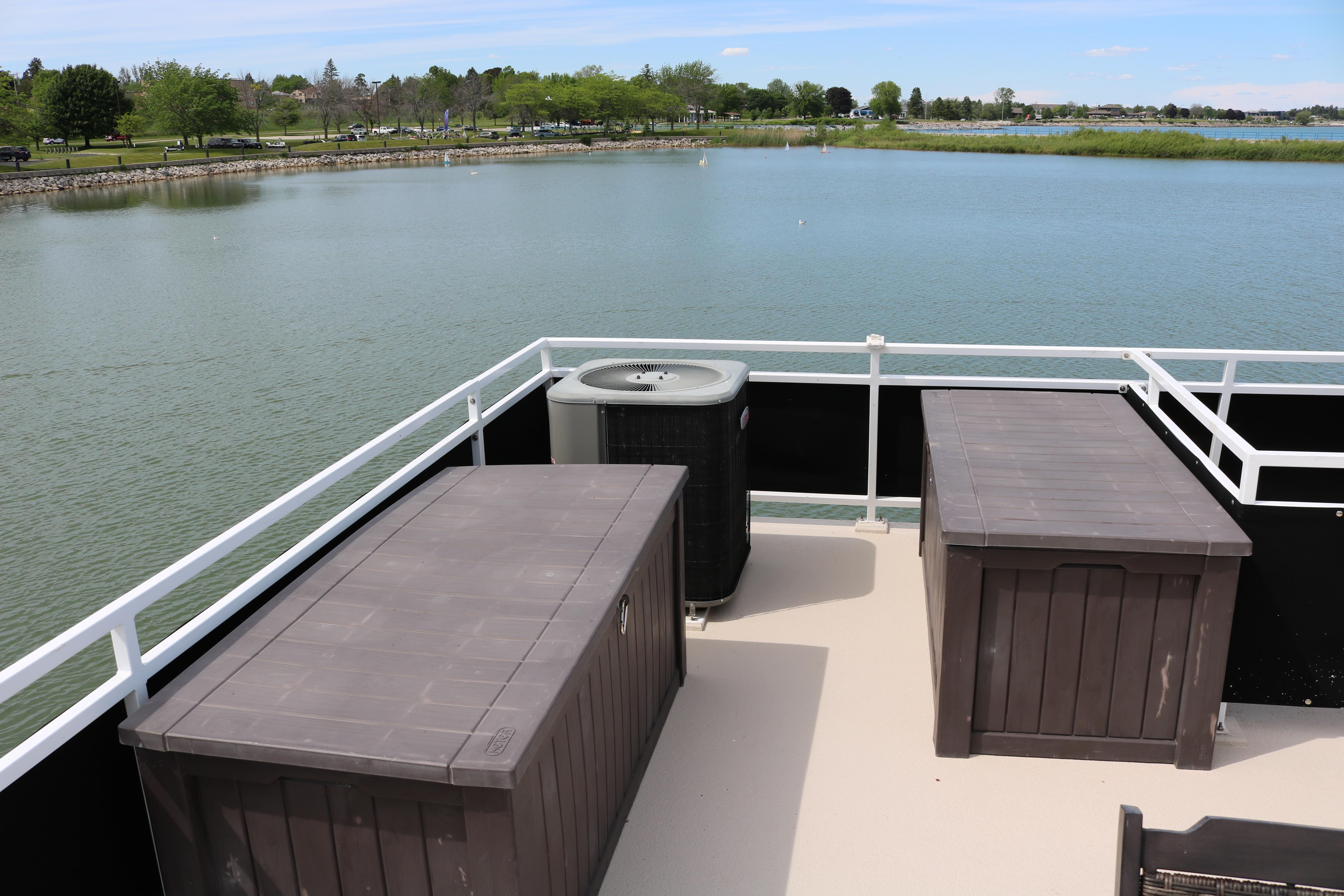 Flybridge deck of 2010 Skipperliner 480 with storage boxes, overlooking serene lake view.