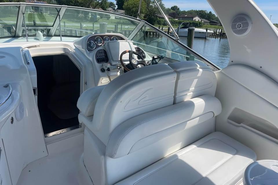 2003 Sea Ray 300 Sundancer cockpit with white seating and steering wheel, docked by the water.