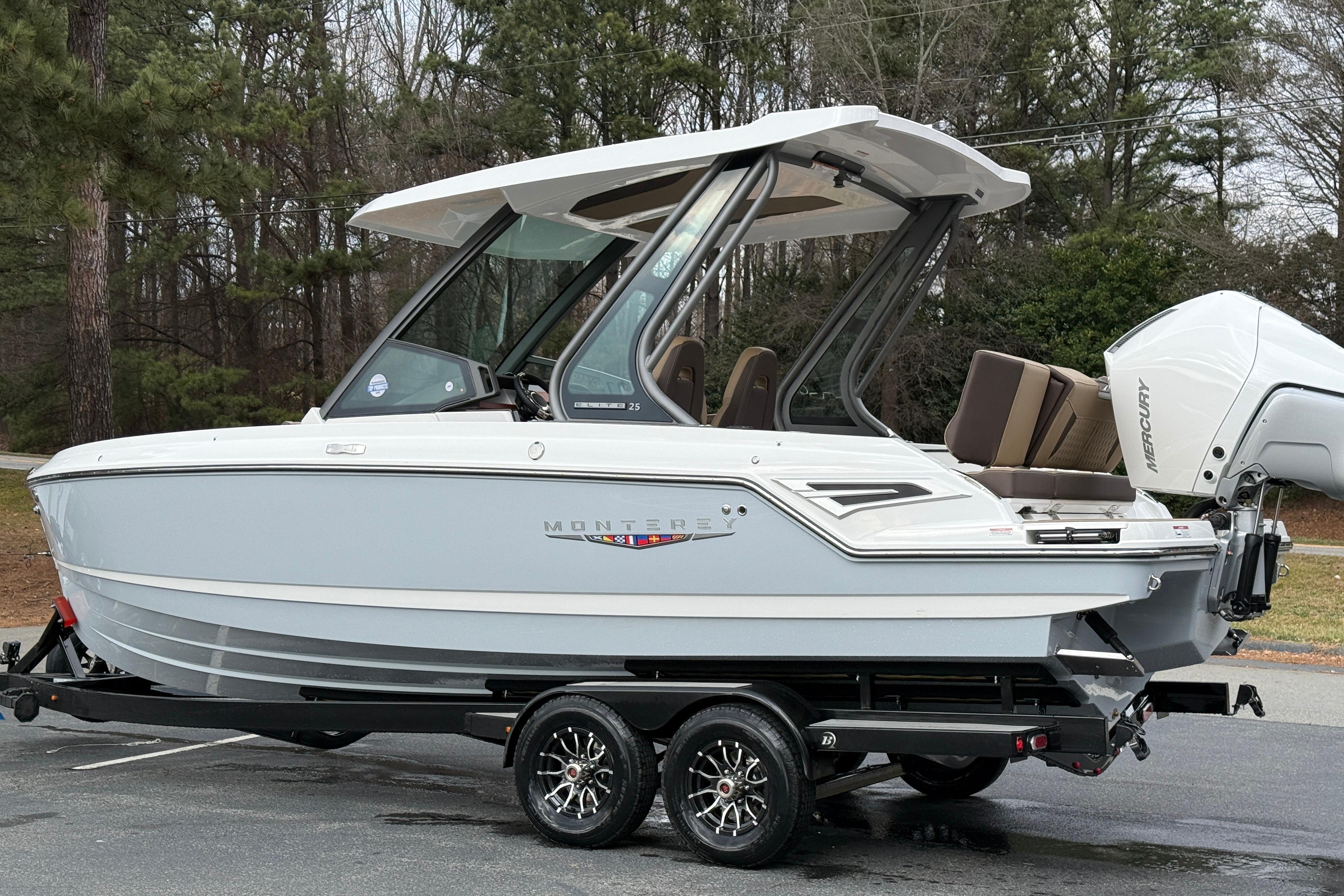2026 Monterey Elite 25 OB boat on trailer, parked outdoors, featuring sleek design and modern outboard motor.