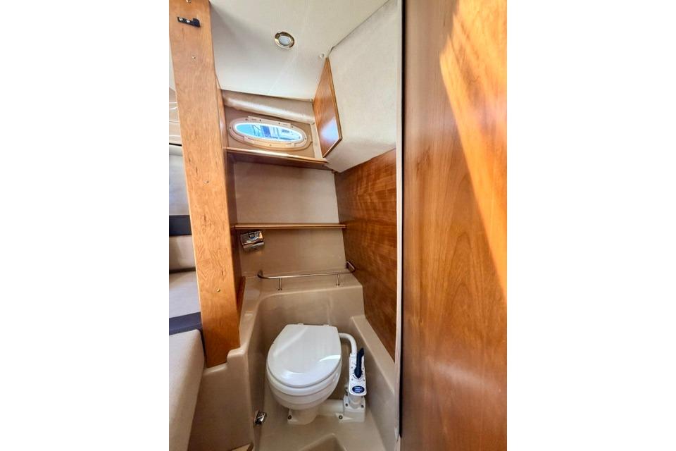 2017 Cutwater C-242 Coupe boat interior bathroom with wooden accents and compact toilet.