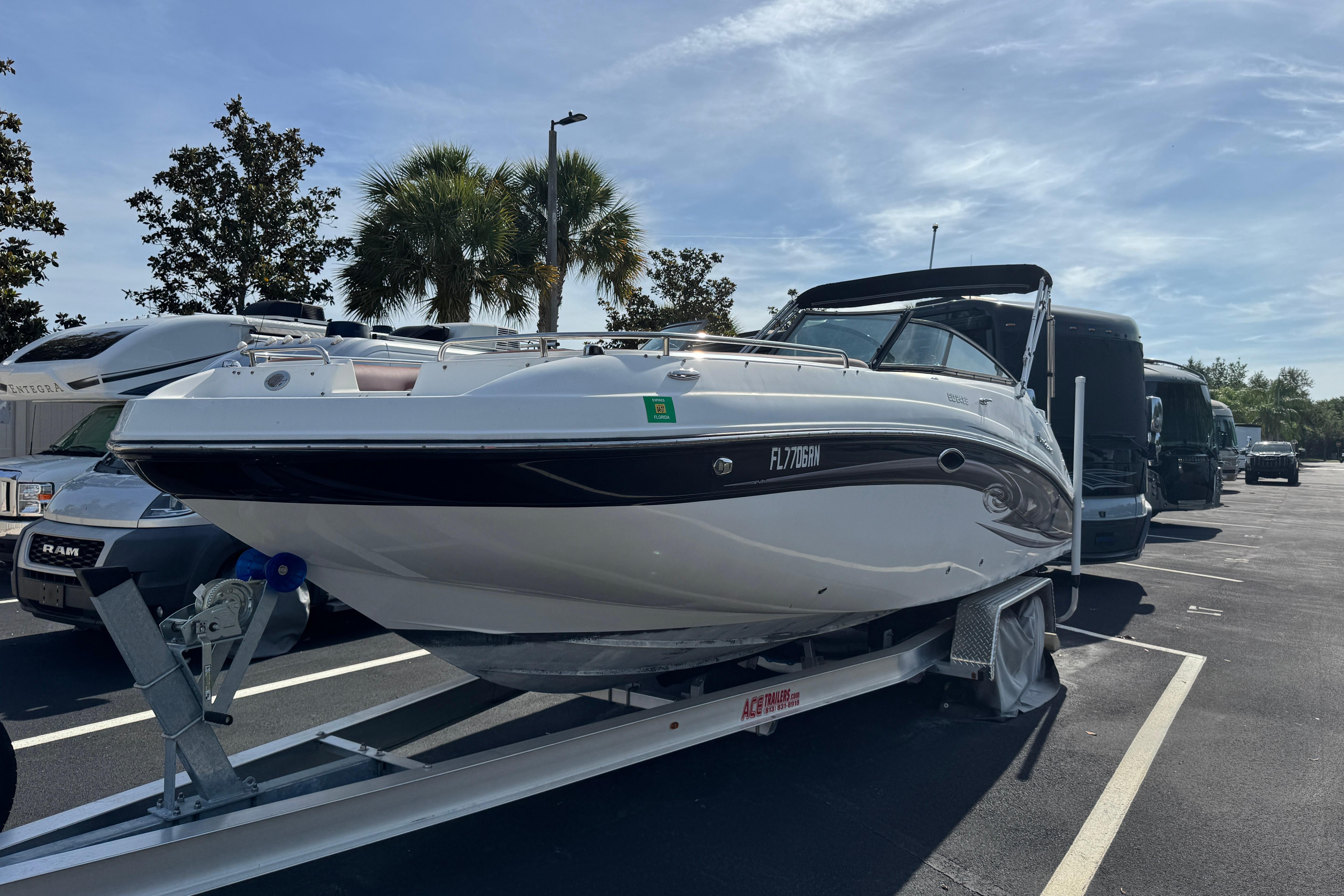 2018 Hurricane SunDeck 2400 OB boat on trailer in parking lot, sunny day.