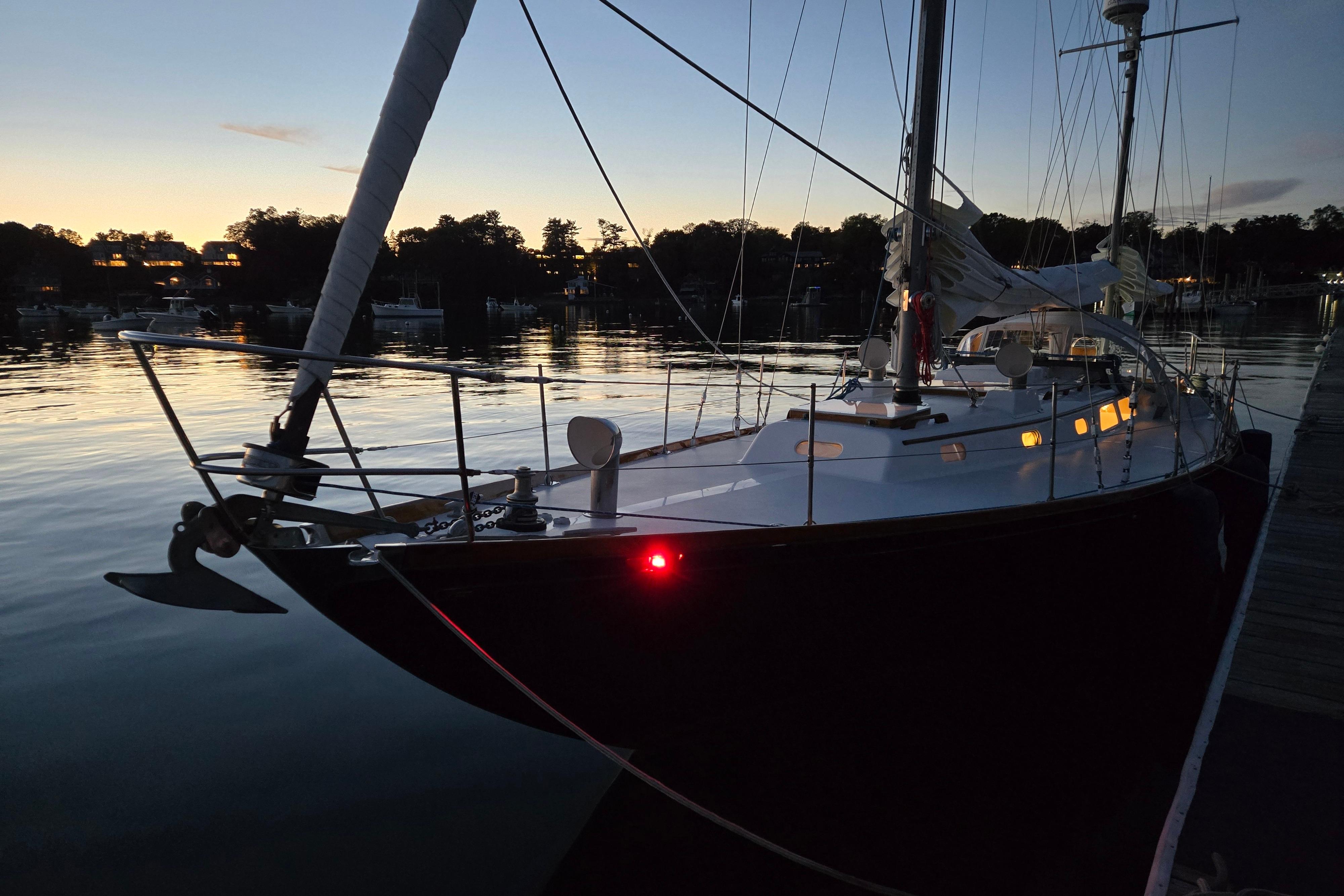 1970 Hinckley Bermuda 40 sailboat docked at sunset, reflecting on calm water.