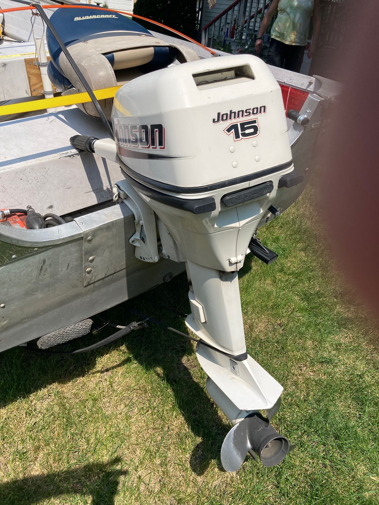 A boat with a Johnson 15 outboard motor on grass.