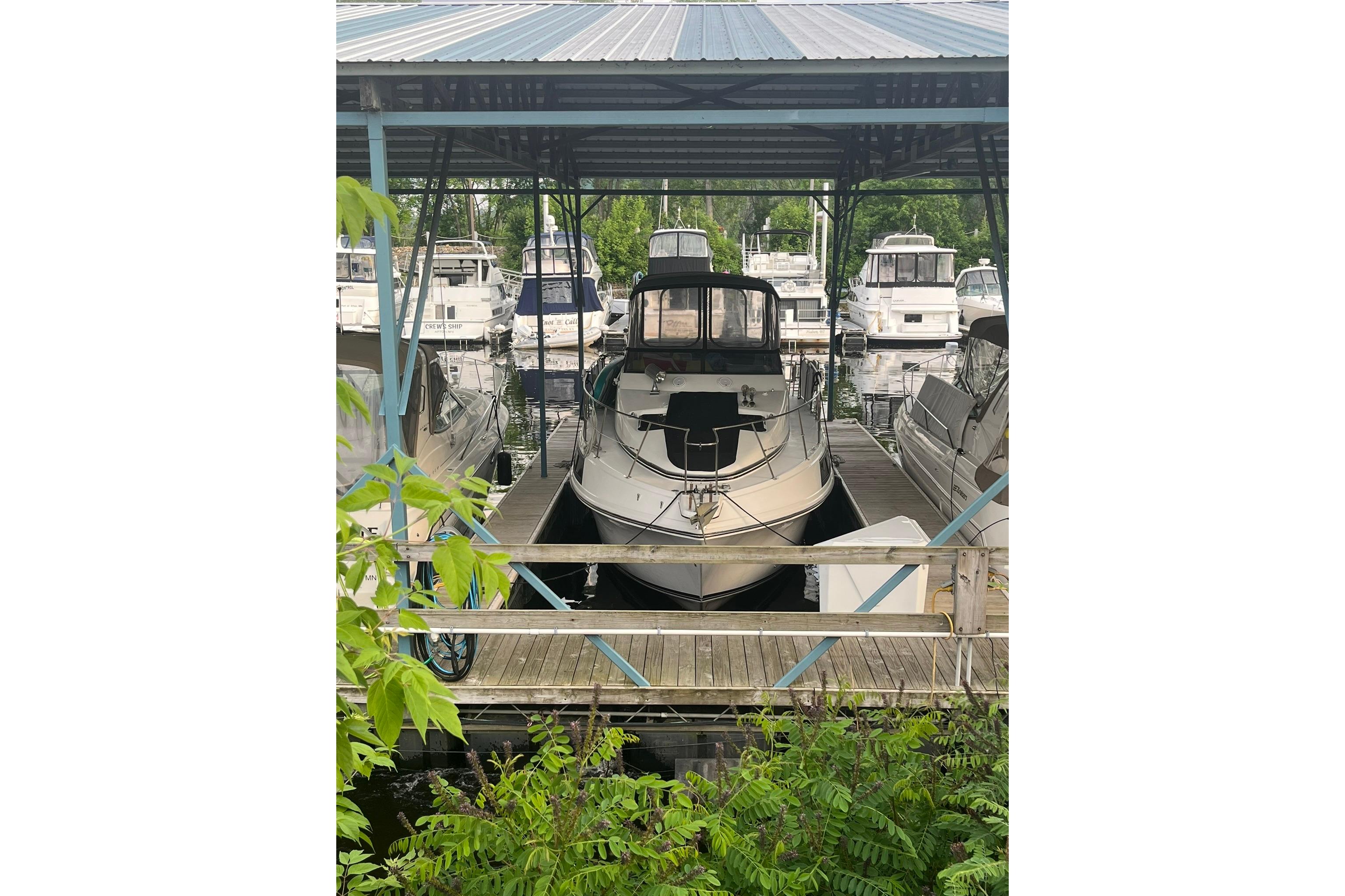 1986 Carver 3297 Mariner docked at a marina, surrounded by lush greenery.