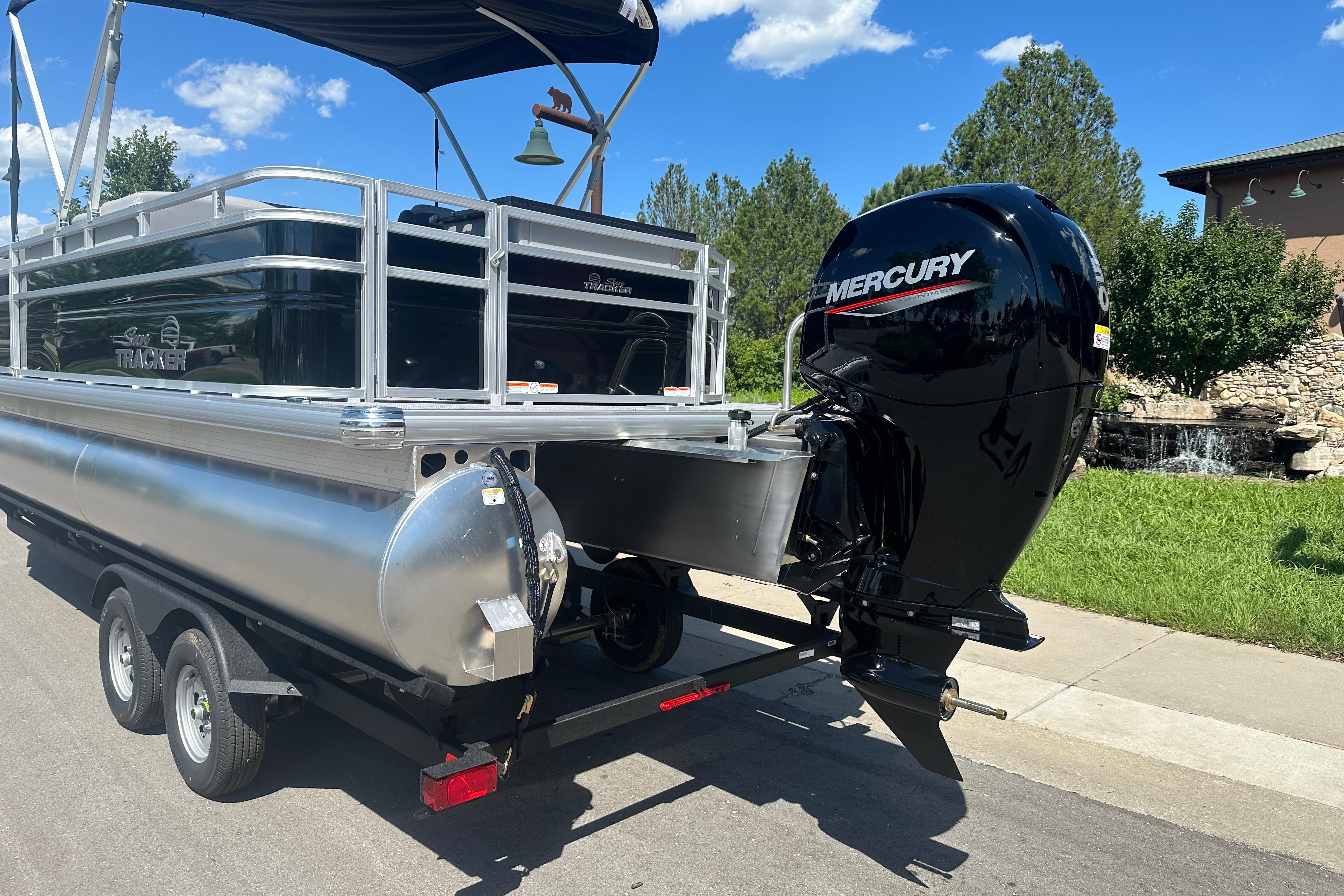 2026 Sun Tracker SportFish 22 DLX pontoon boat with Mercury outboard motor on trailer.