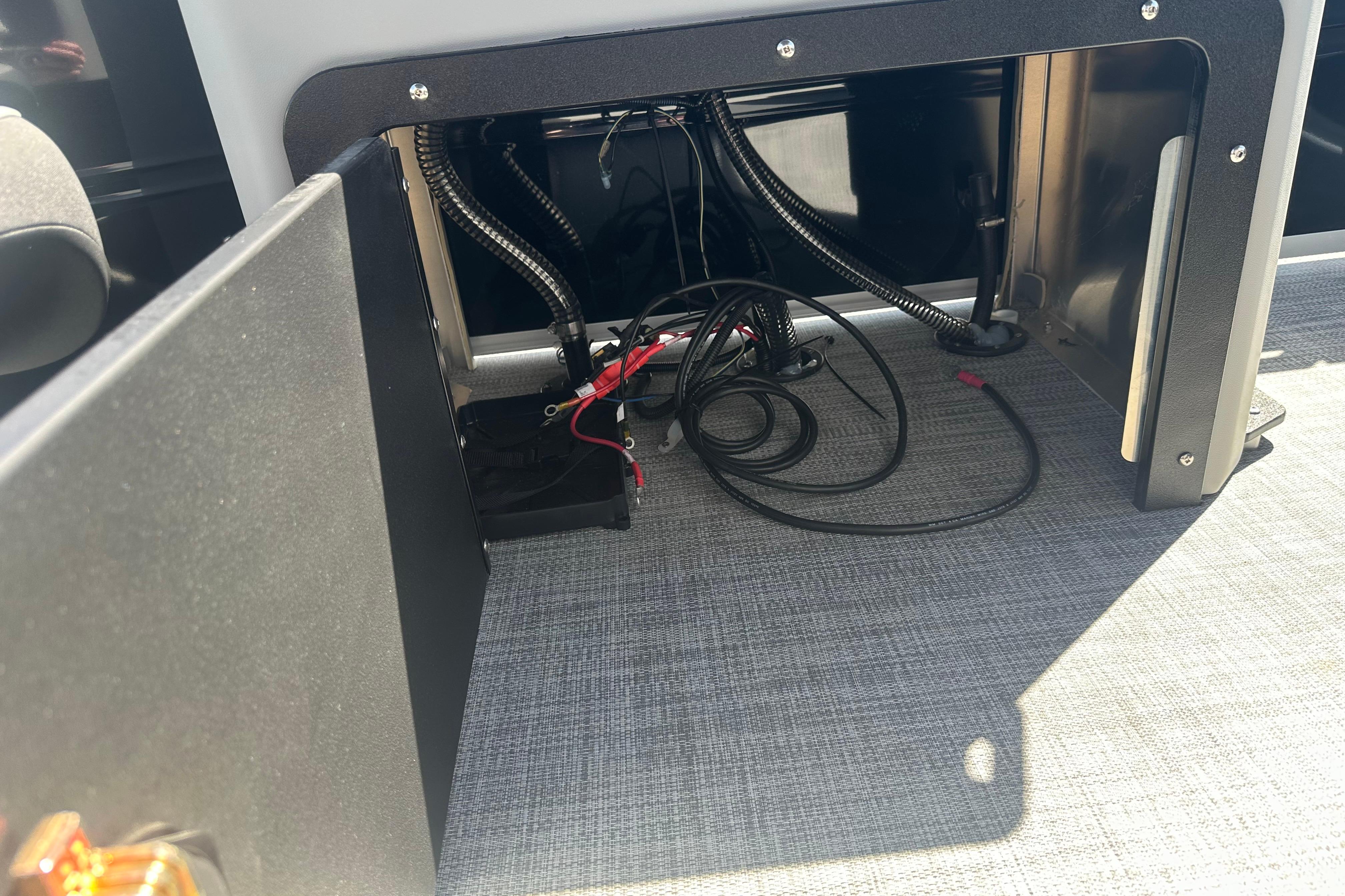Open compartment with wiring inside a 2026 Sun Tracker SportFish 22 DLX boat.