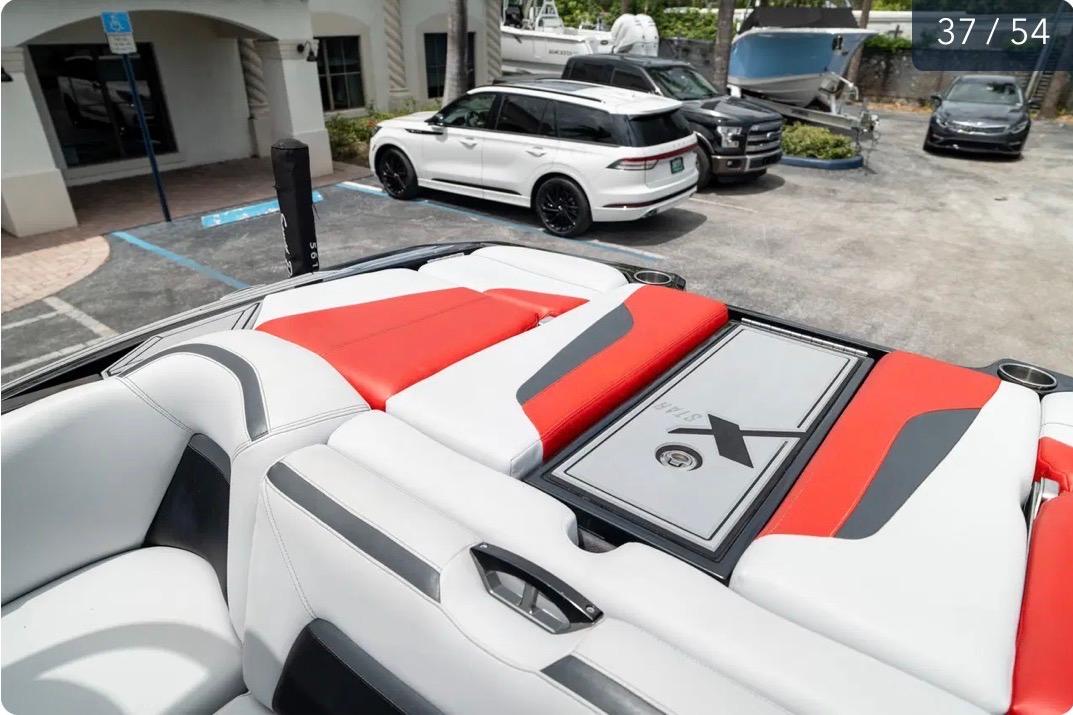 2019 MasterCraft XStar boat interior with red and white seating, parked cars in the background.