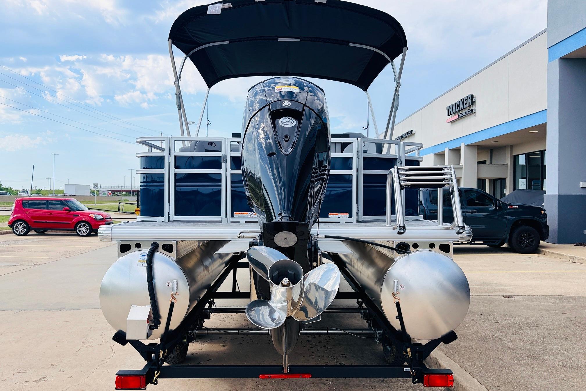 2026 Sun Tracker SportFish 22 DLX pontoon boat with outboard motor, parked at dealership.