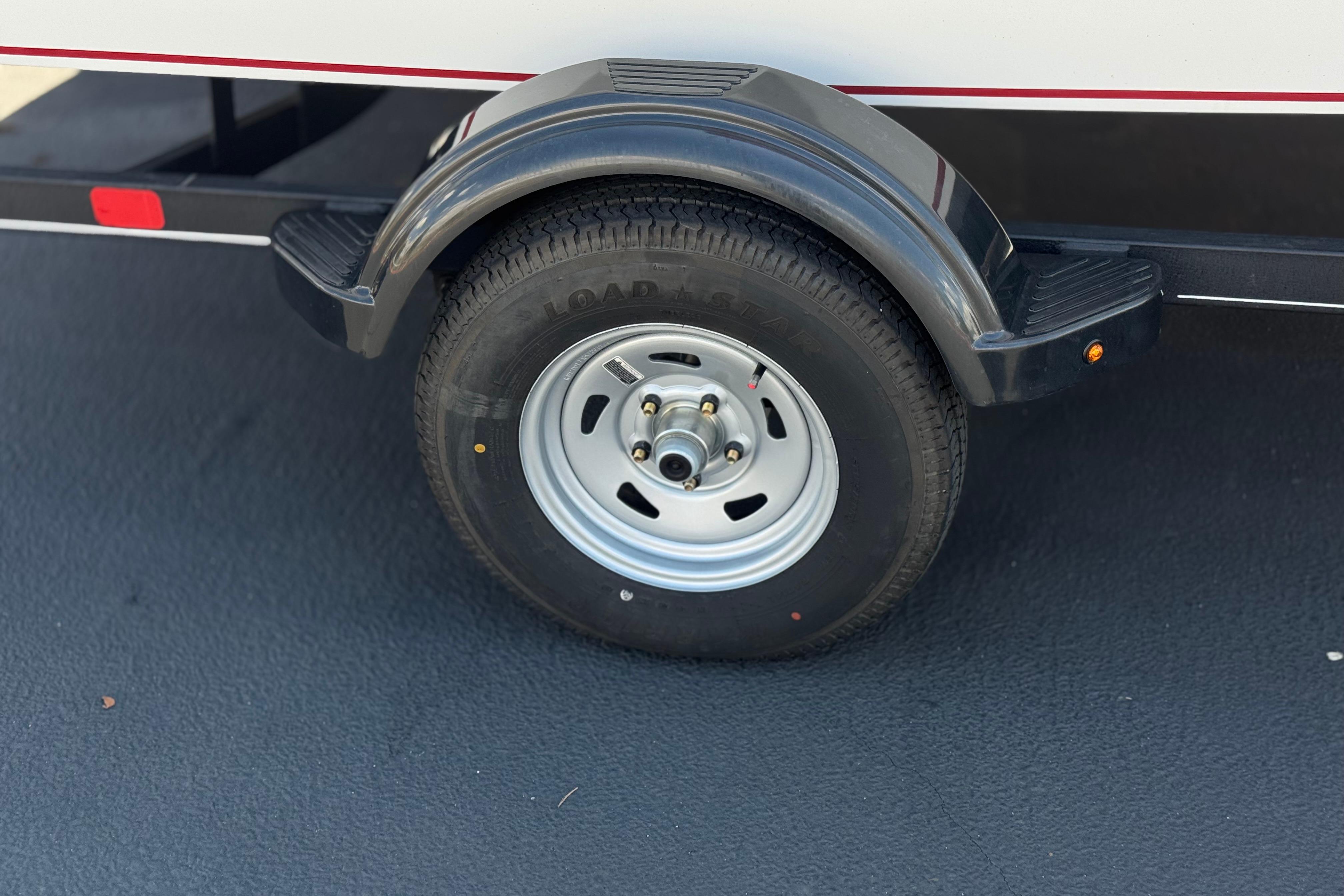 2024 Tahoe T16 trailer wheel with black fender on asphalt surface.