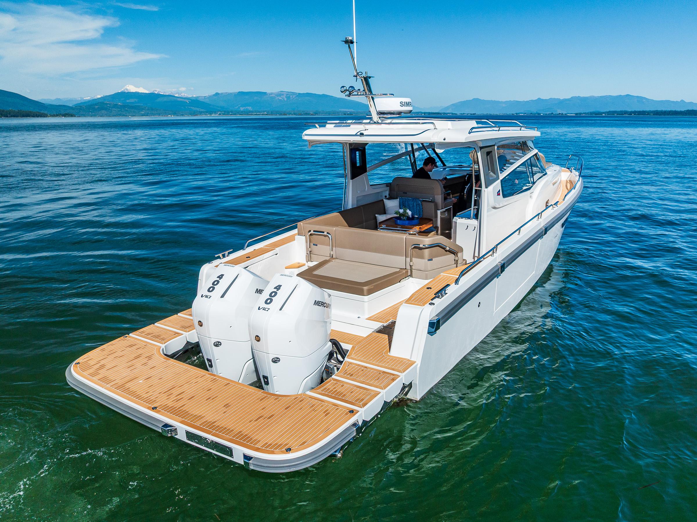 Nimbus W11 2025 motorboat cruising on clear blue water with scenic mountain backdrop.