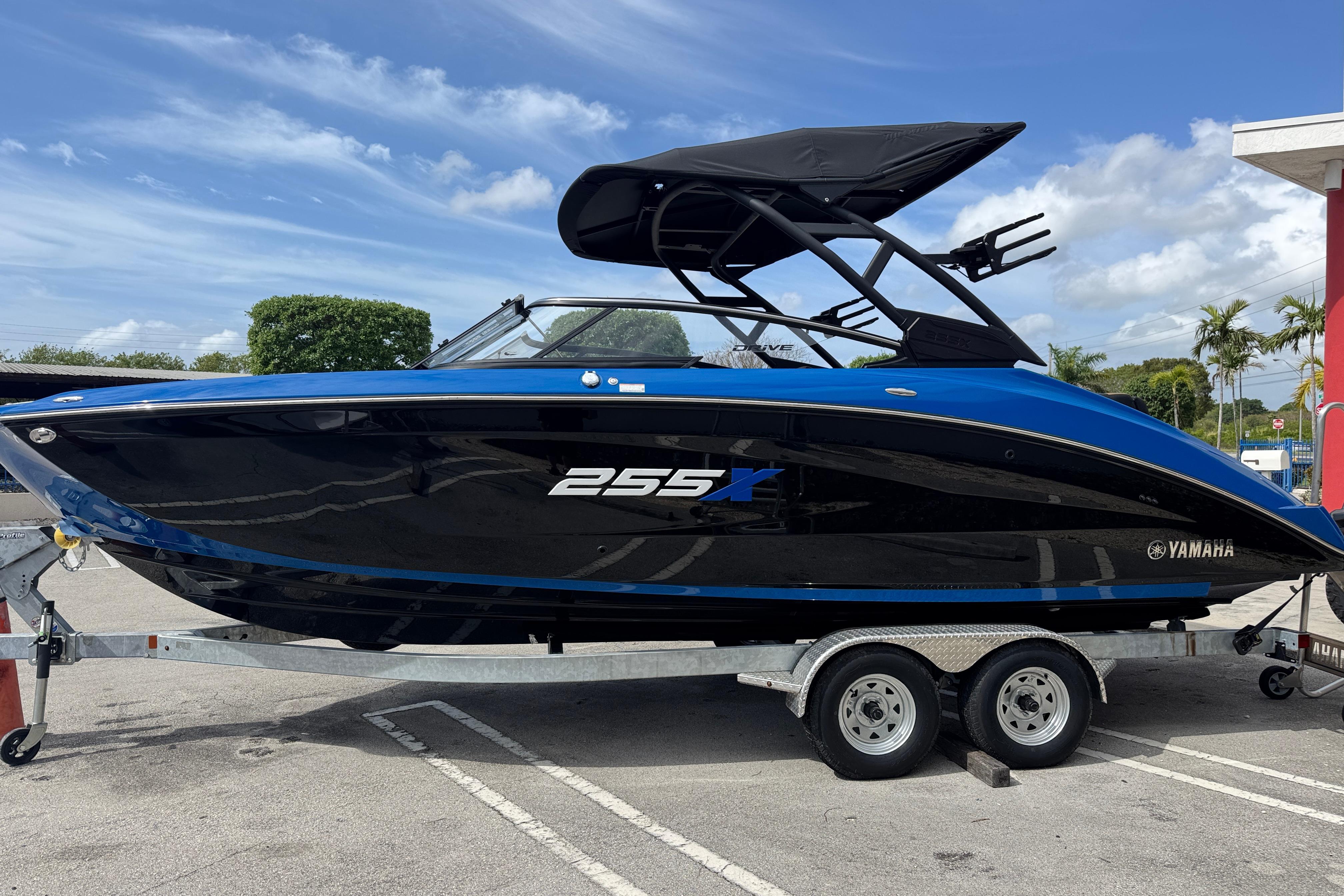 2026 Yamaha Boats 255XD on trailer, sleek black and blue design, parked outdoors.