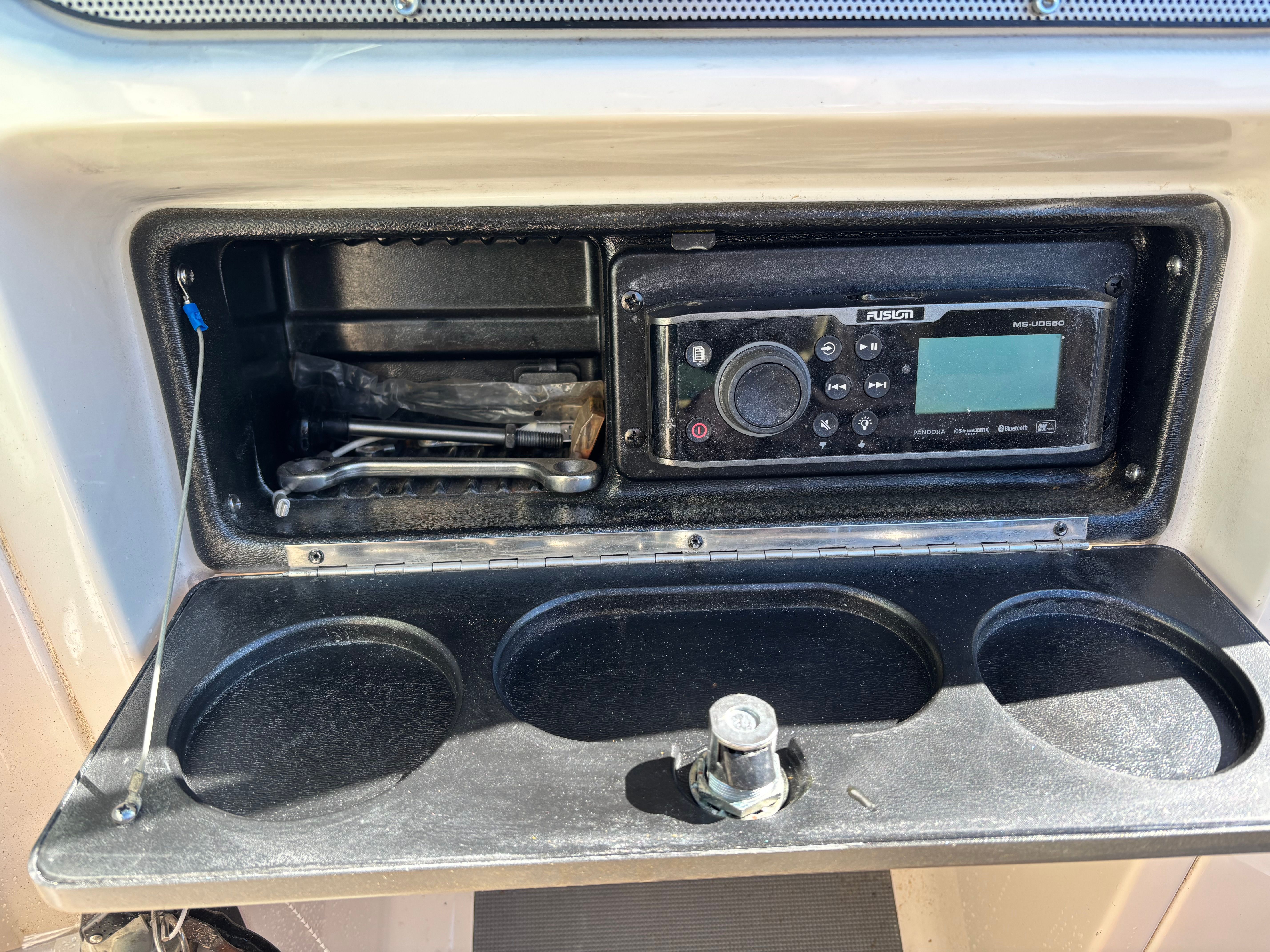 An open storage compartment with a Fusion marine radio and holders.