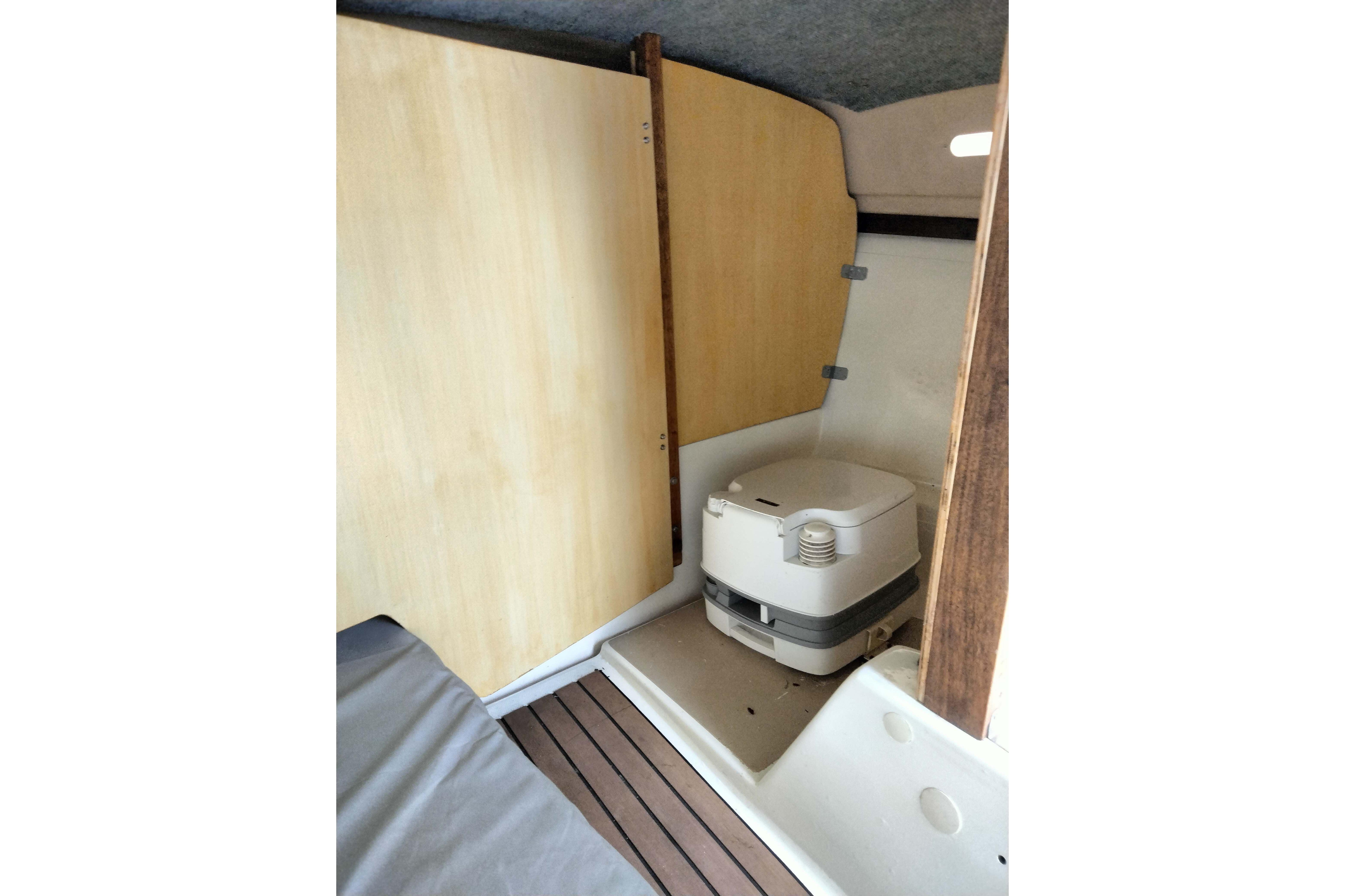 Interior of a 1980 MacGregor 25 sailboat featuring a compact marine toilet.