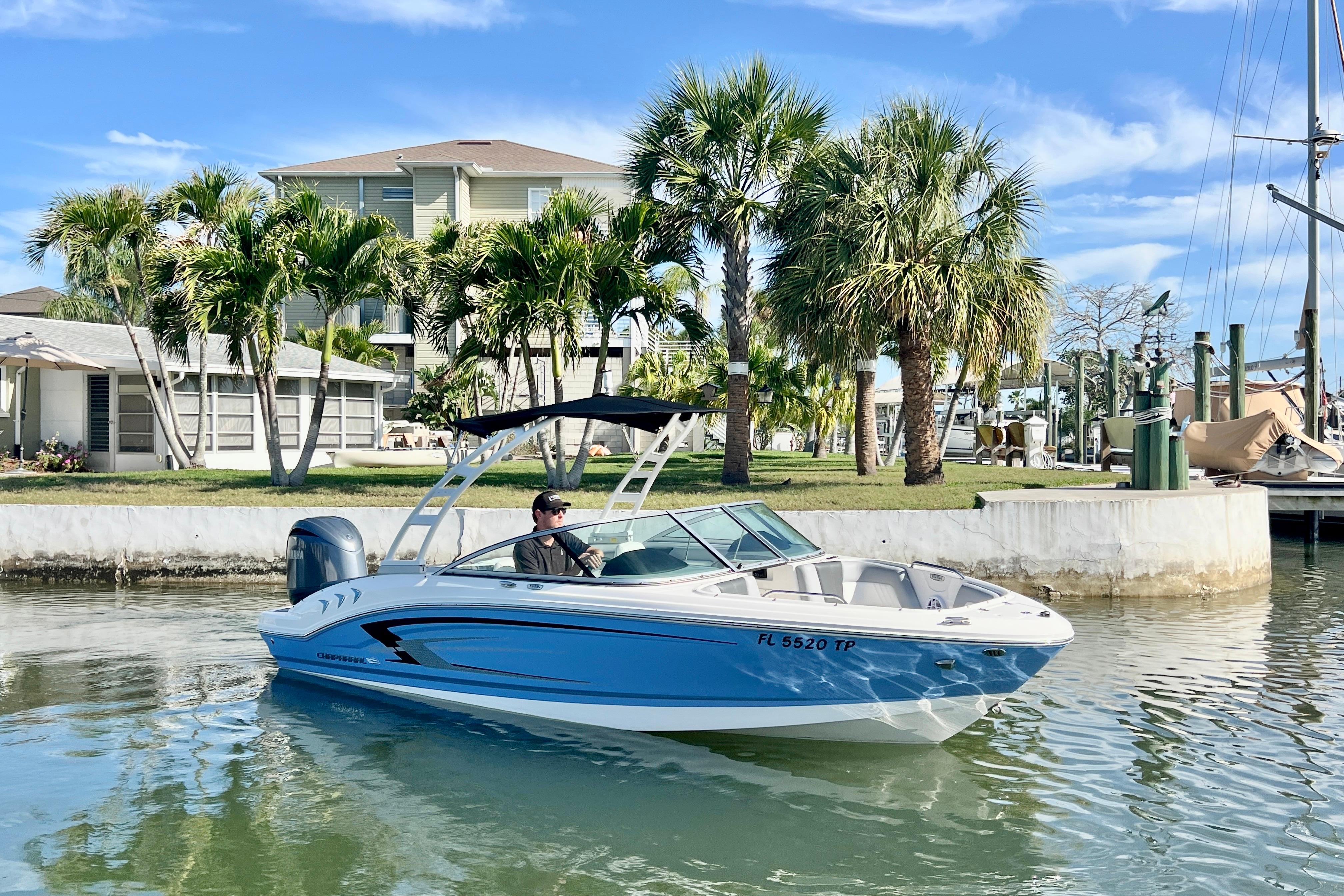 2023 Chaparral 21 SSi OB boat cruising near palm trees and waterfront homes.