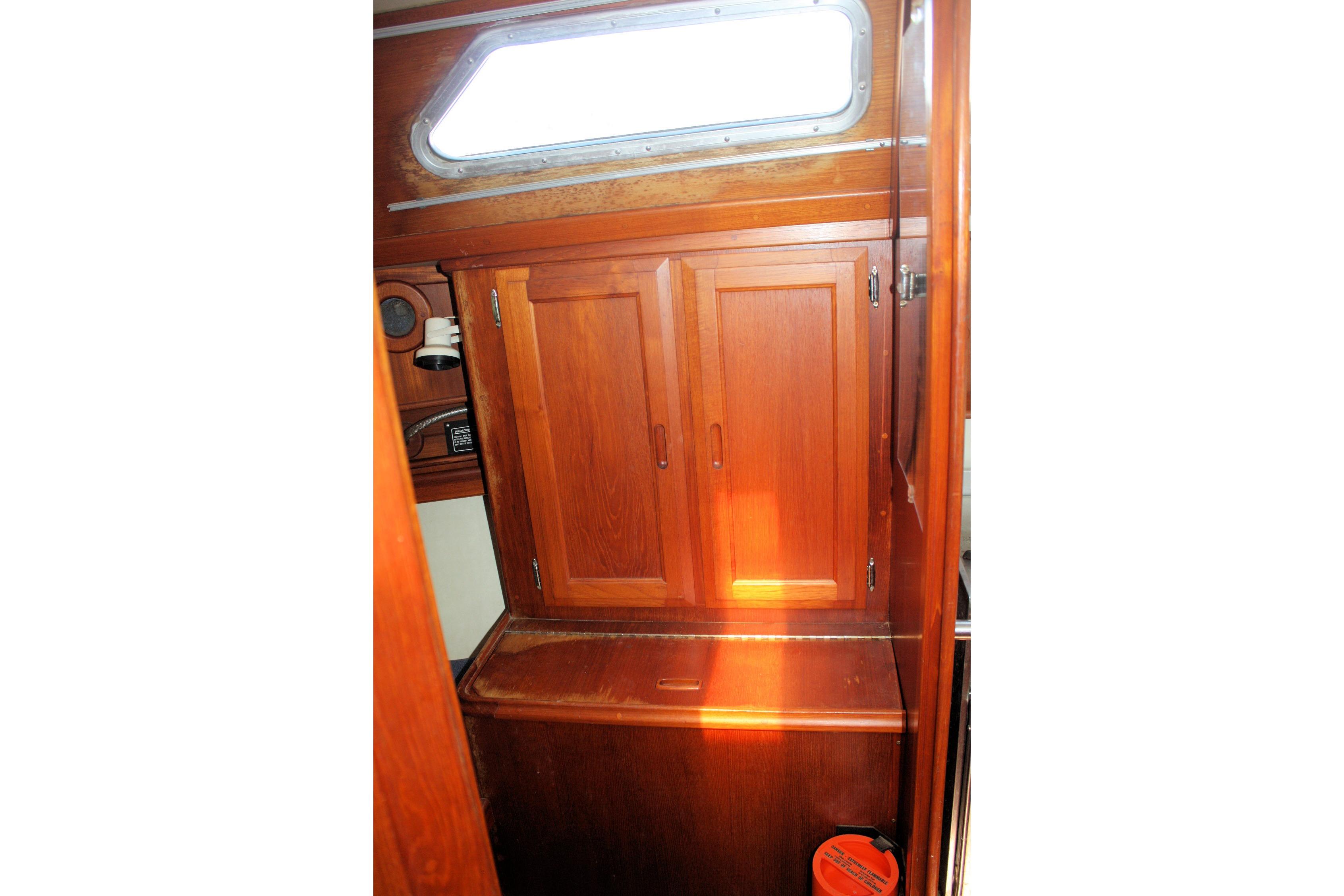 Interior of 1987 Ericson 38-200 sailboat featuring wooden cabinetry and a porthole window.