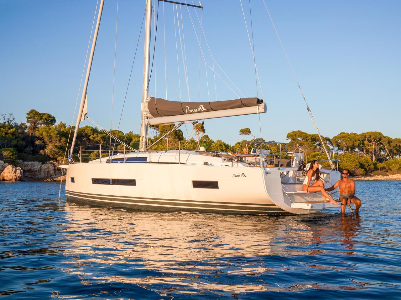 2025 Hanse 410 sailboat anchored in serene waters with people relaxing.