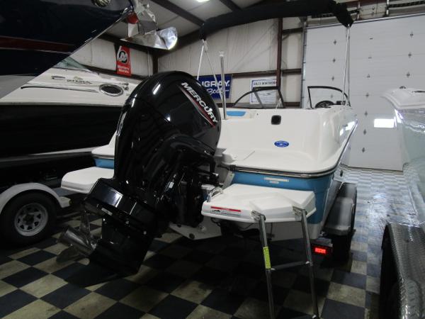 2023 Bayliner 210EL boat with Mercury outboard motor in a showroom.