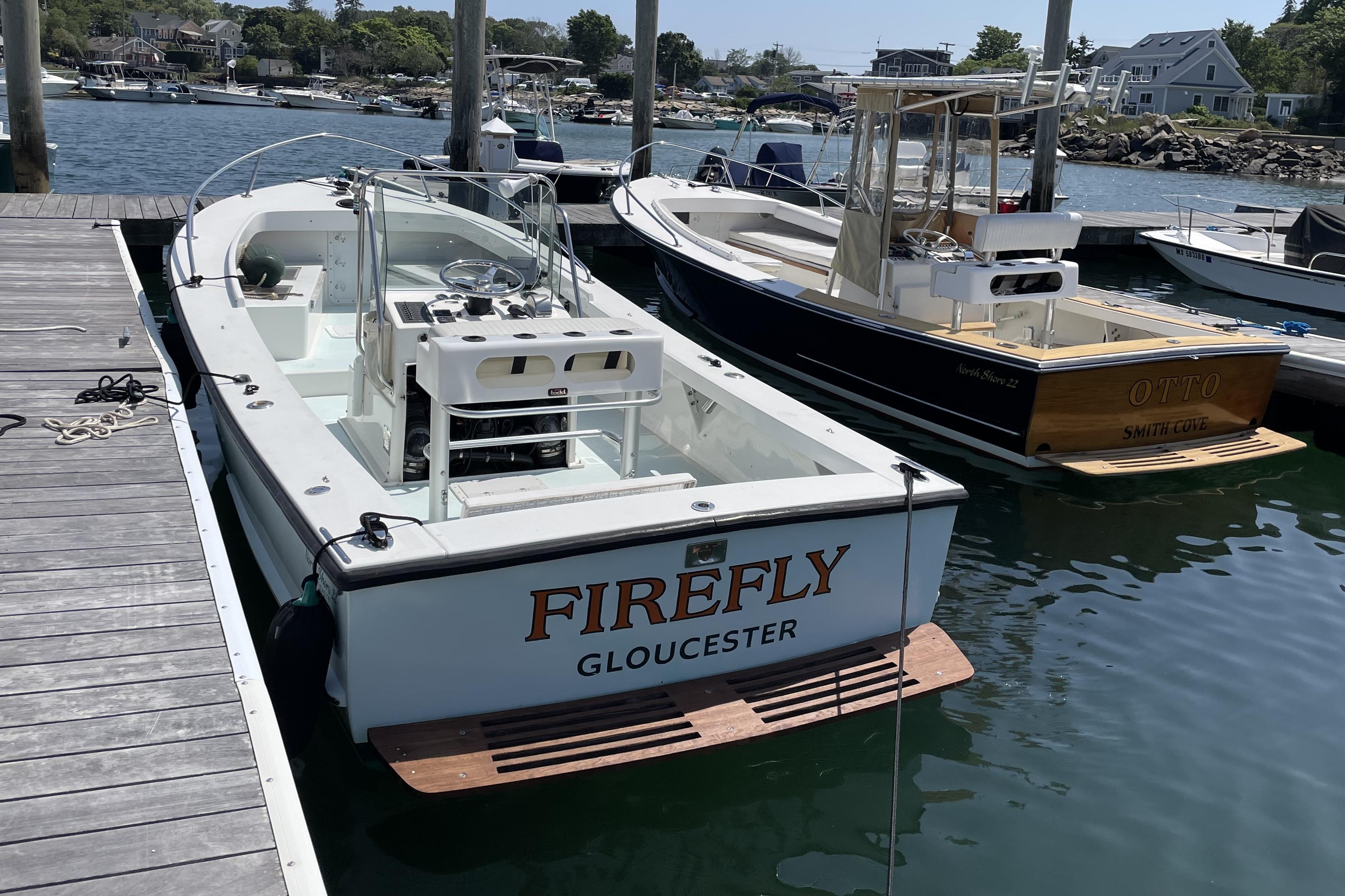 Two boats docked, including a 1999 Northshore 22, in a scenic harbor setting.