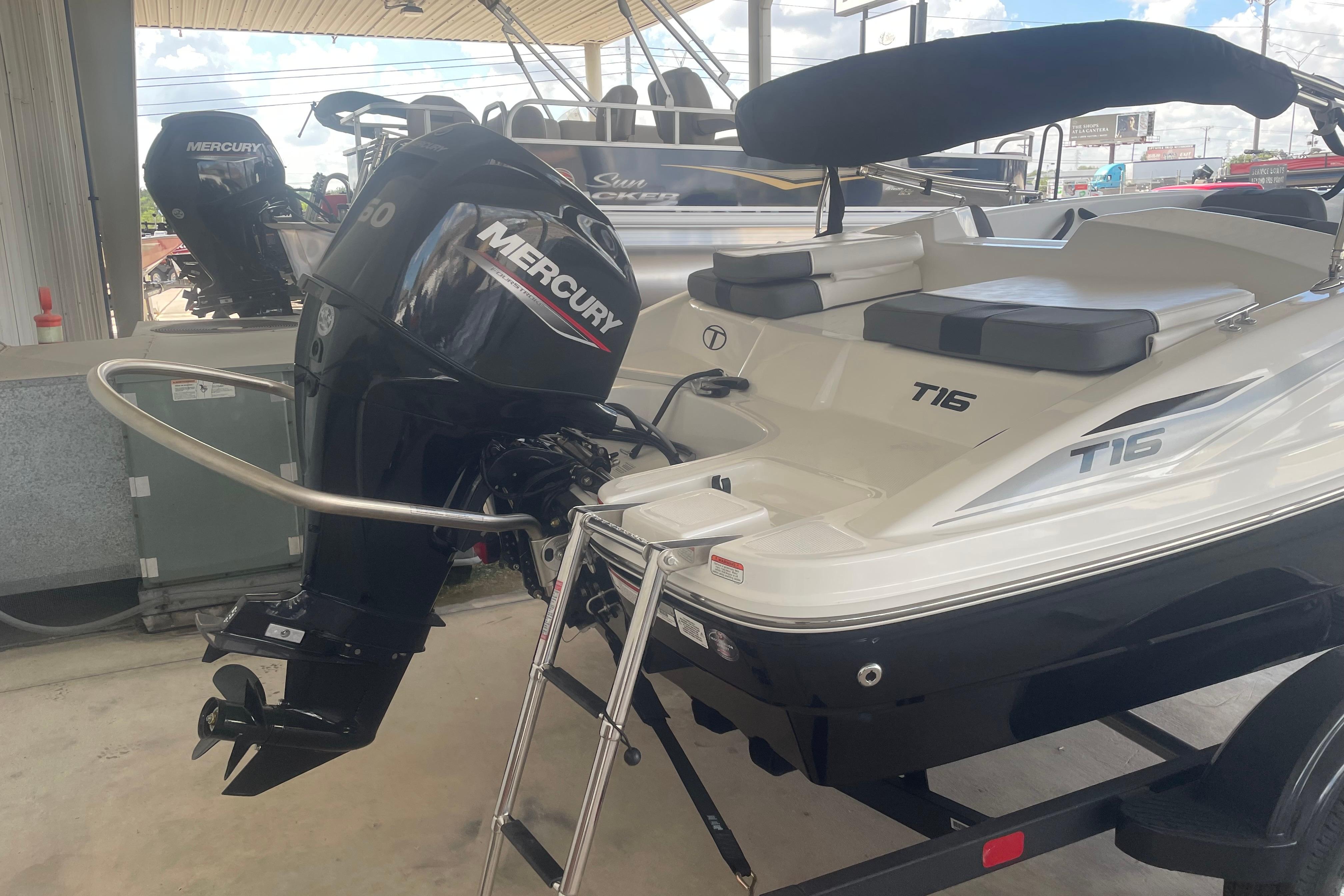 2026 Tahoe T16 boat with Mercury outboard motor, displayed in a showroom.