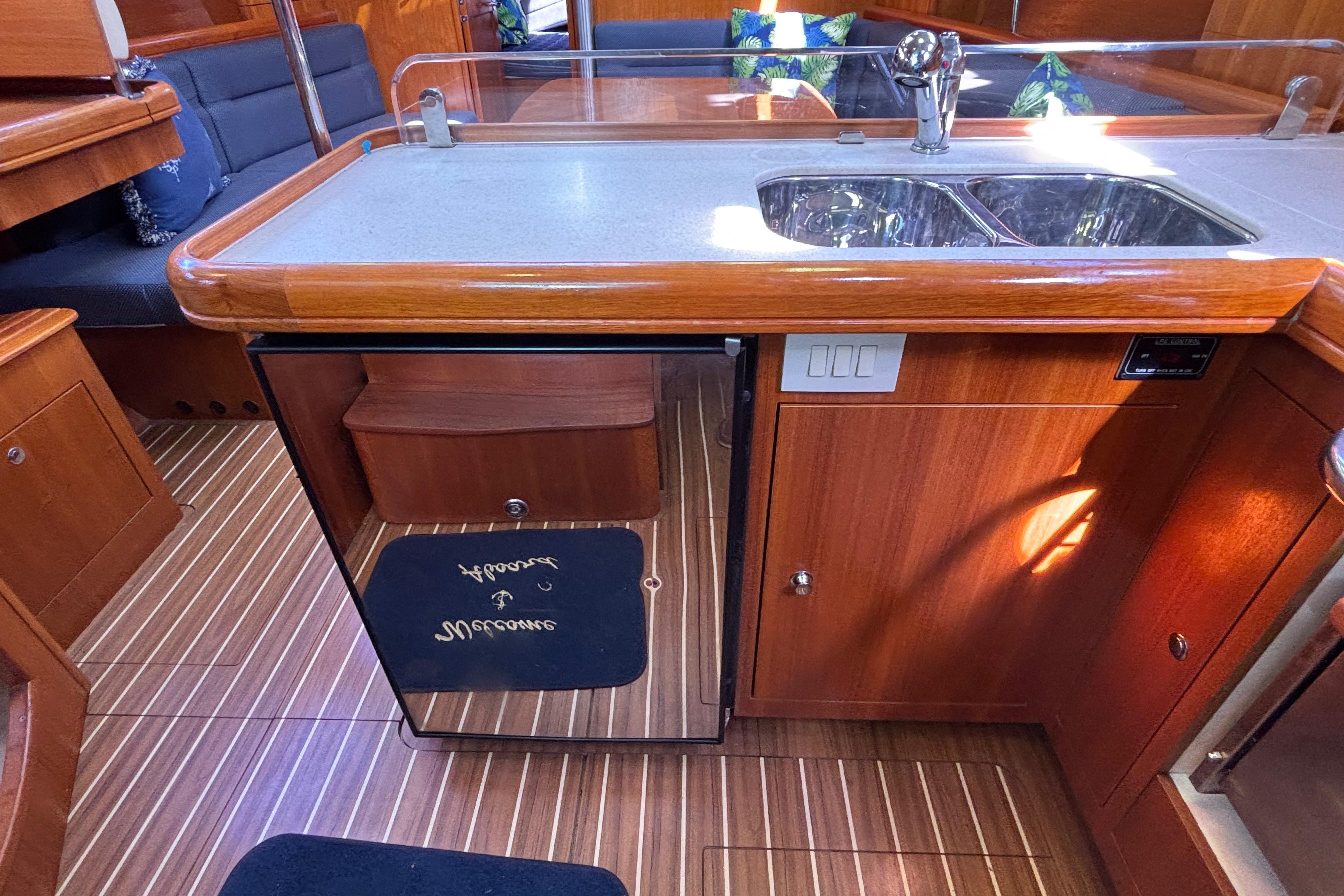 Interior of 2006 Hunter 38 sailboat kitchen with wood finish and dual sink.