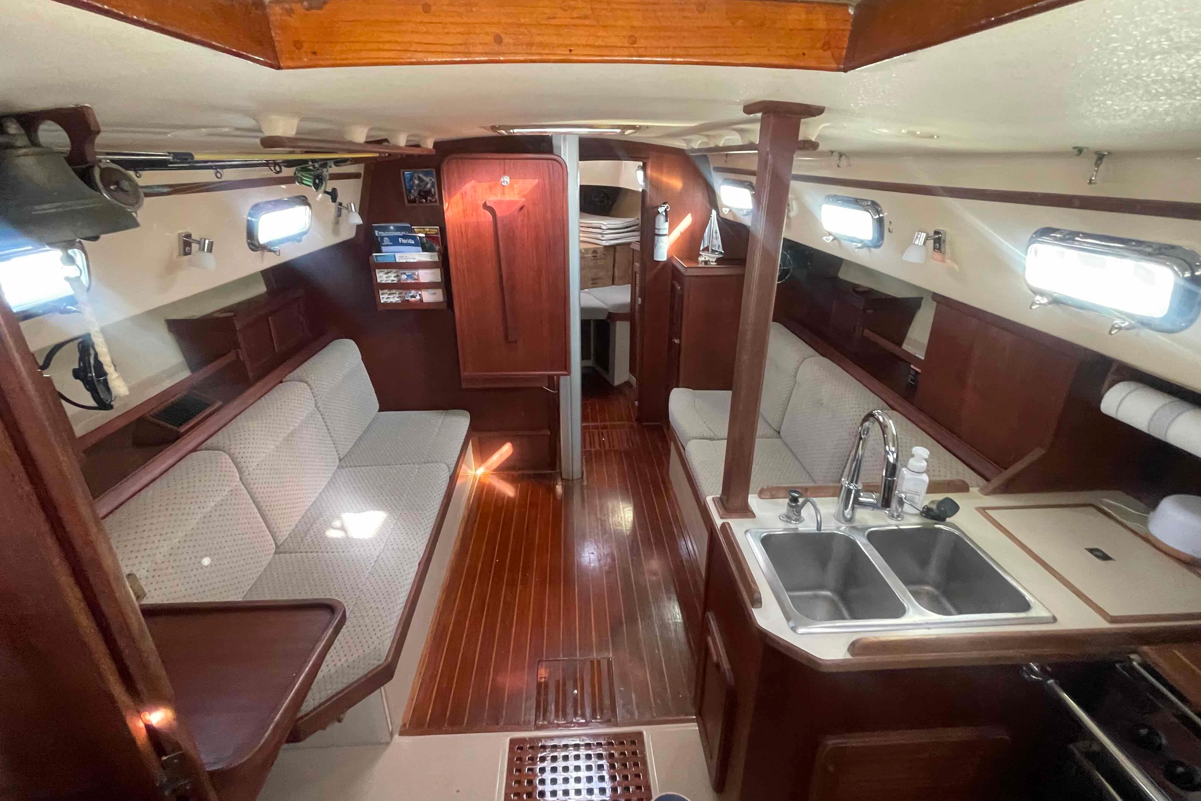 1989 Island Packet 35 sailboat interior with wood finish, cozy seating, and kitchen area.