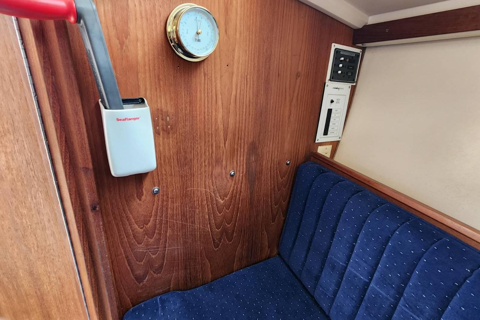 Interior of 1990 Catalina Capri sailboat with wood paneling and blue cushioned seating.
