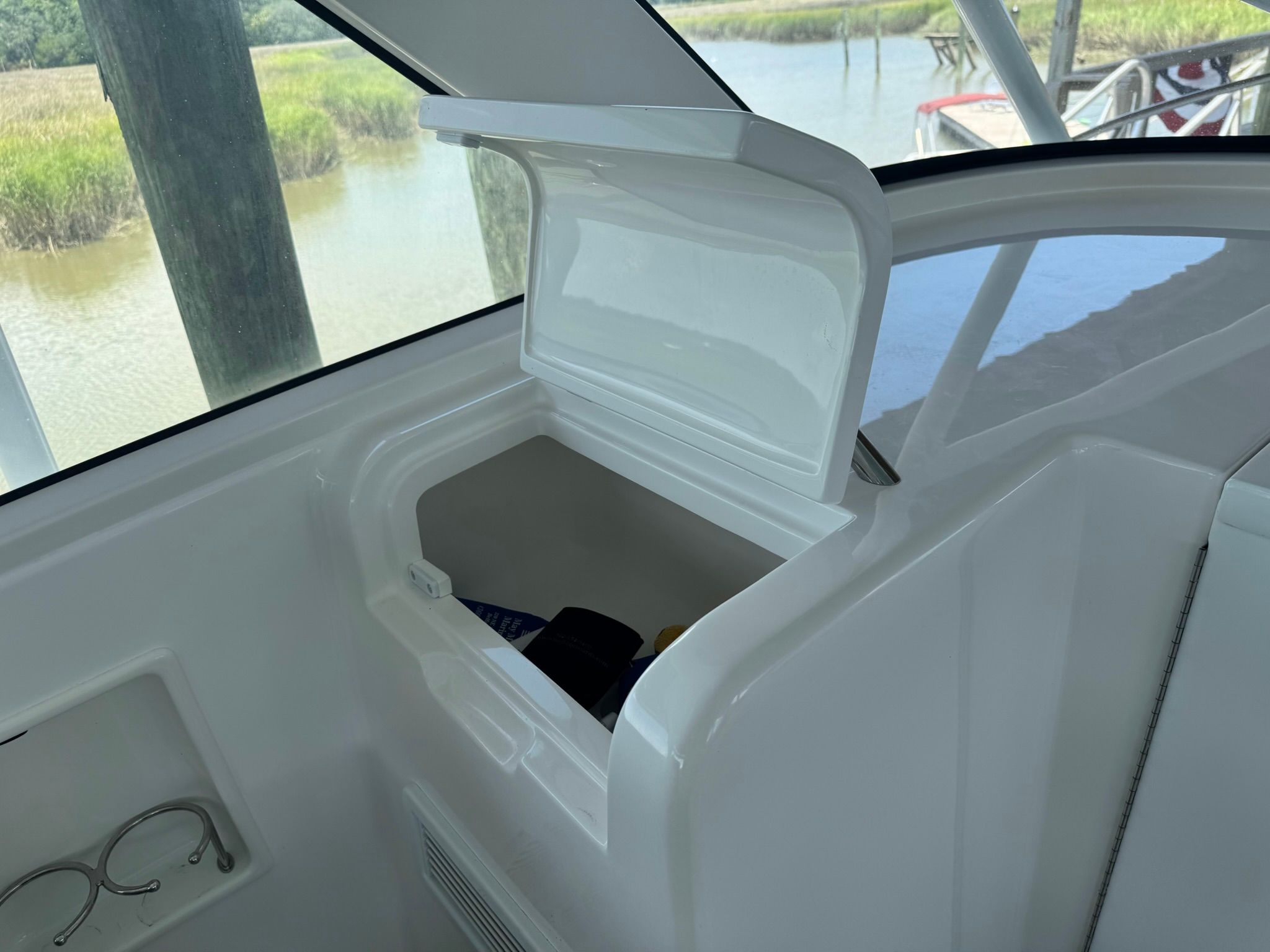 An open storage compartment on a boat with a view of the water in the background.