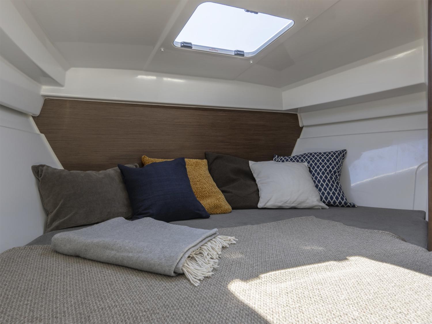 Manufacturer Provided Image: Cozy cabin interior of 2026 Beneteau Antares 7 Fishing boat with cushions and skylight.