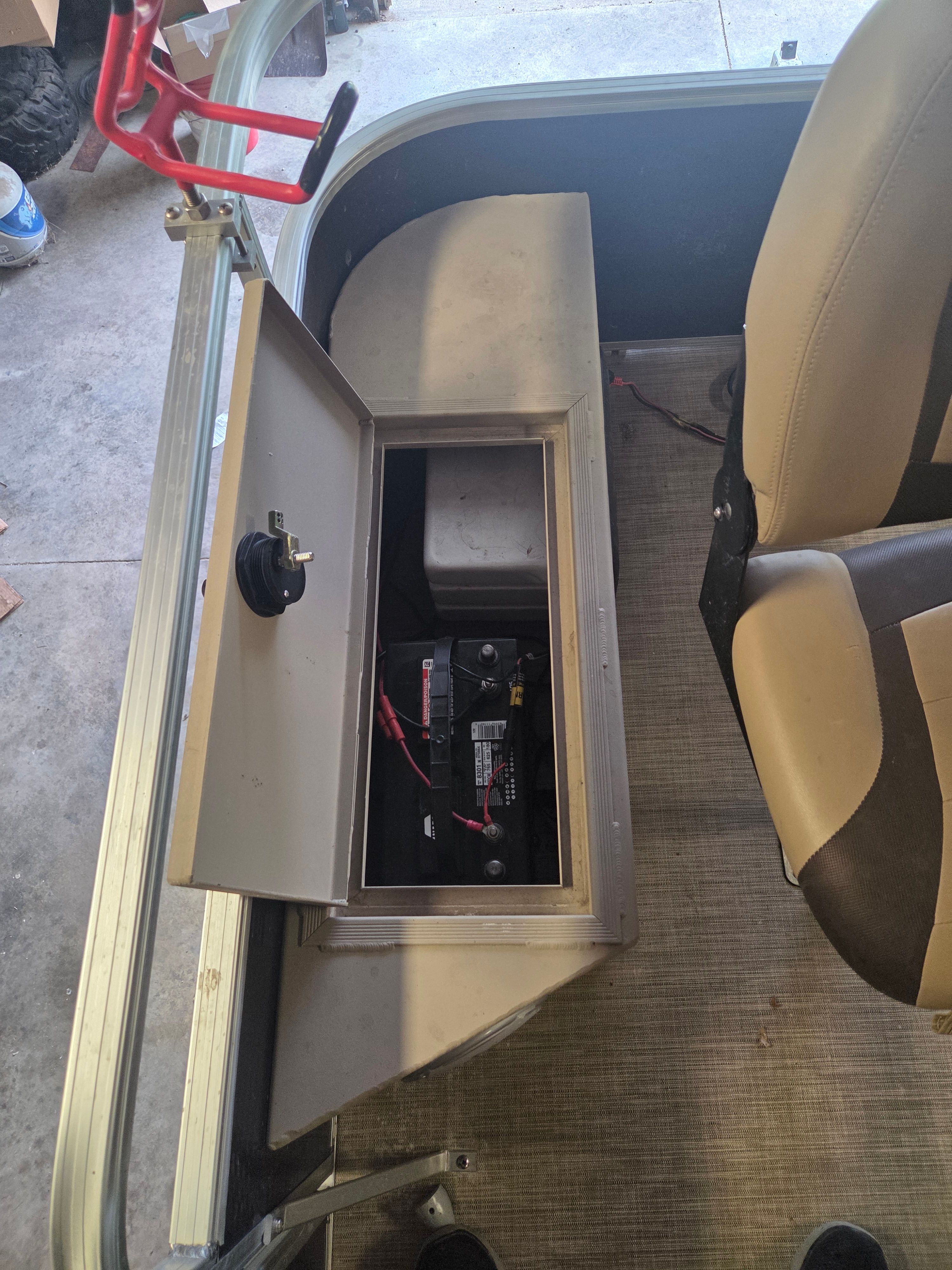 View of a boat's battery compartment with an open lid and cables.